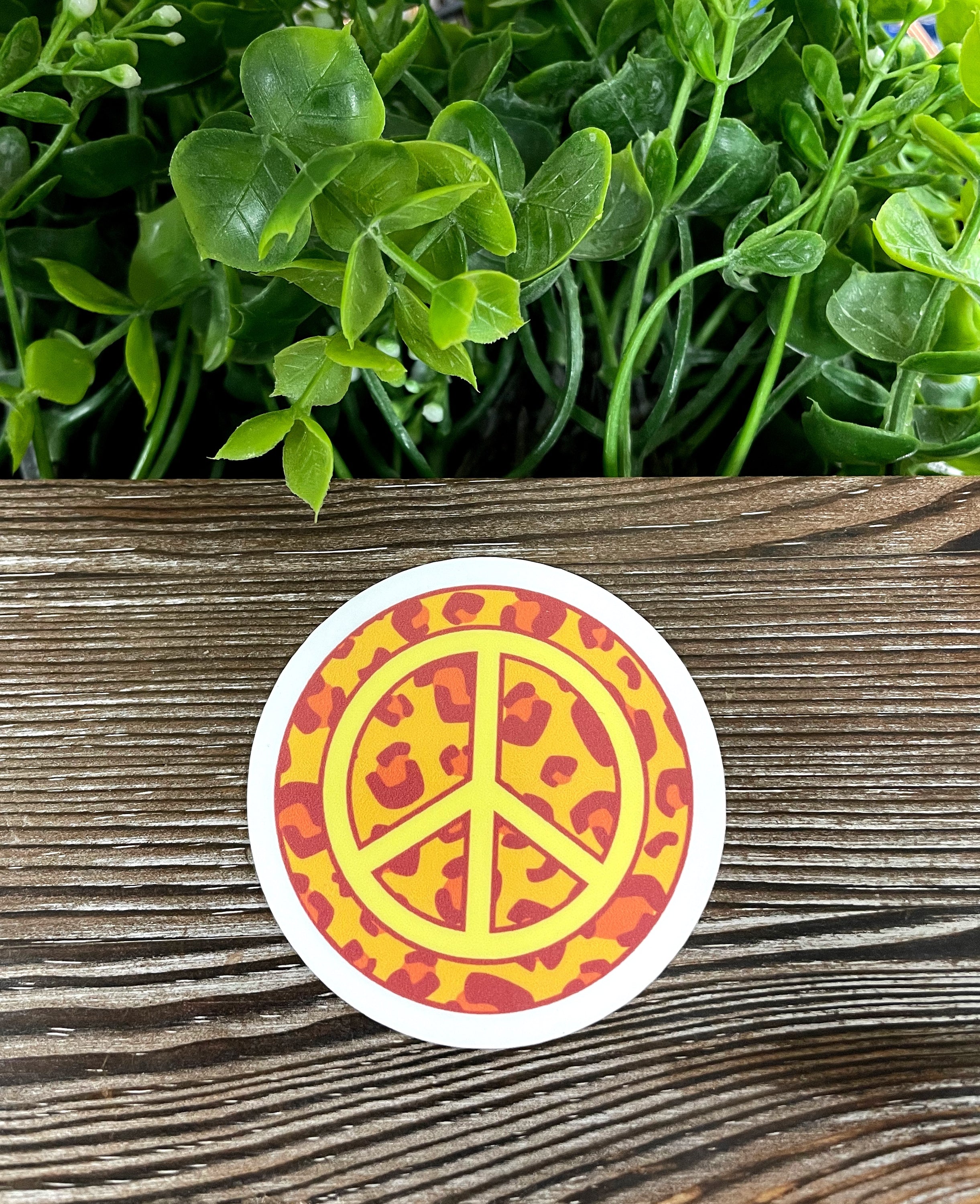 Cheetah print peace sign die cut vinyl sticker on a smooth surface, showcasing vibrant colors and a stylish design.