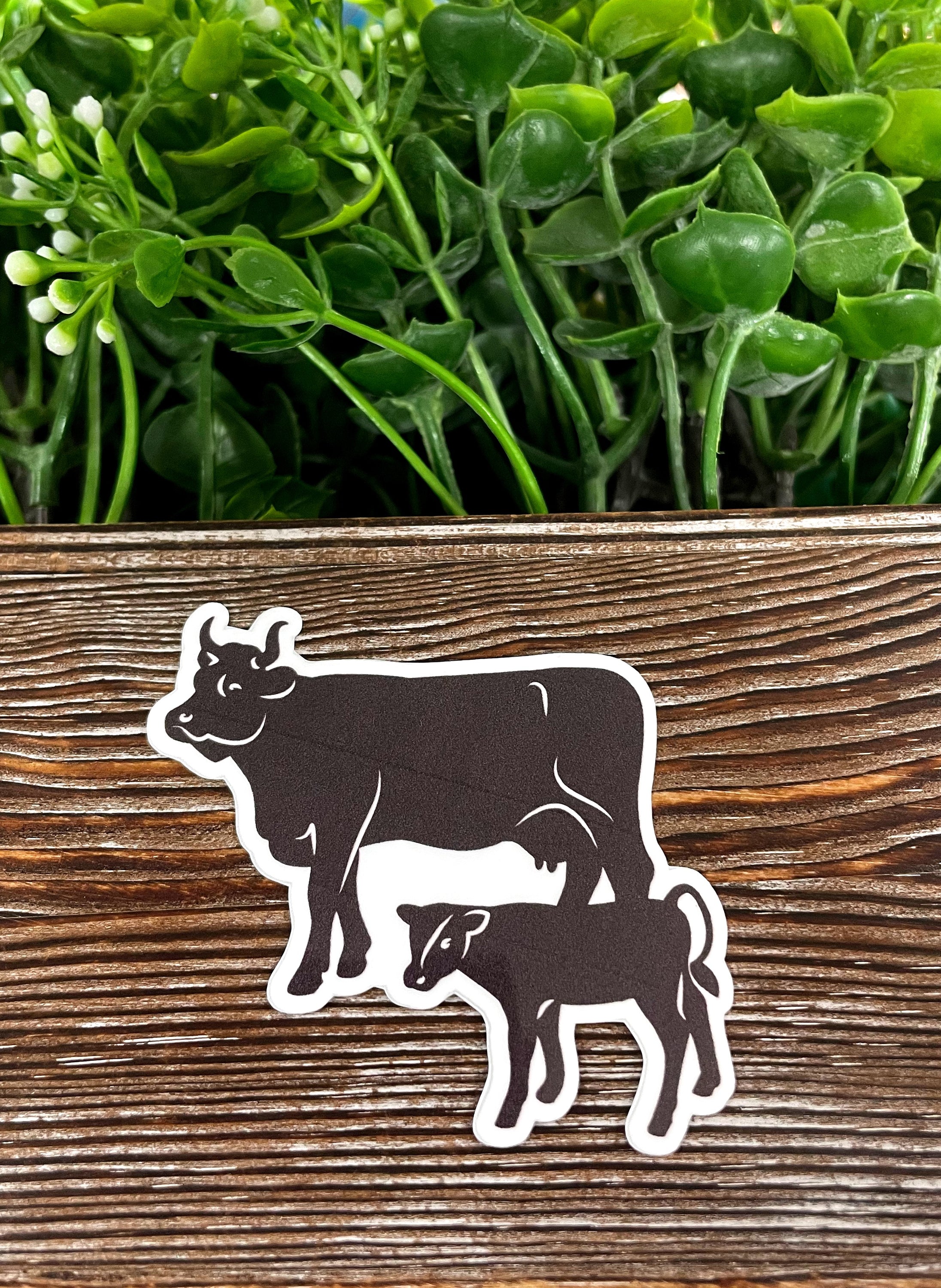 Colorful Cow and Calf Farm Die Cut Vinyl Sticker on a smooth surface, showcasing its vibrant design and water-resistant laminate.