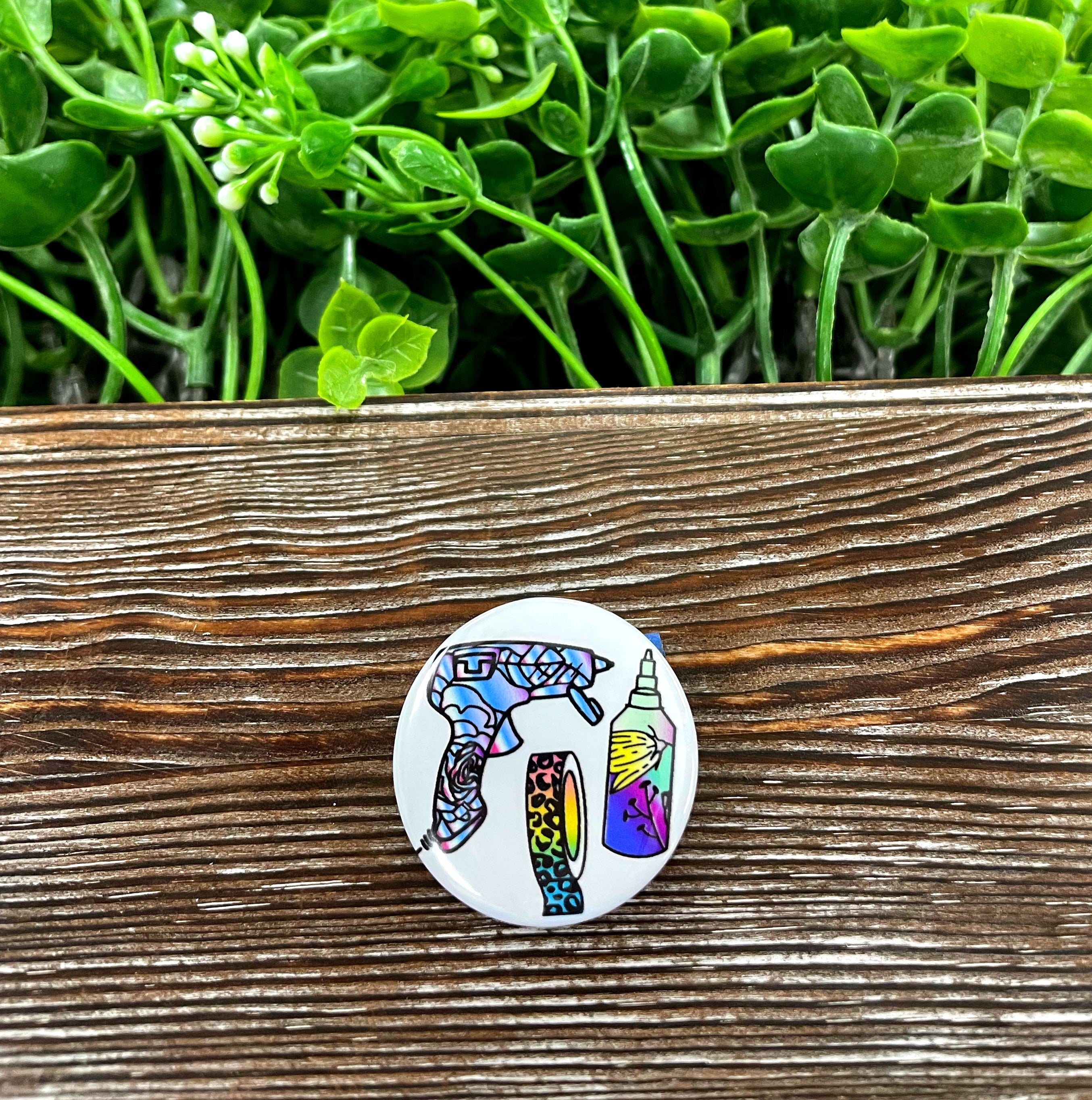 A colorful 1.25-inch graphic art button with a plastic back, showcasing a unique design perfect for personalizing bags and accessories.