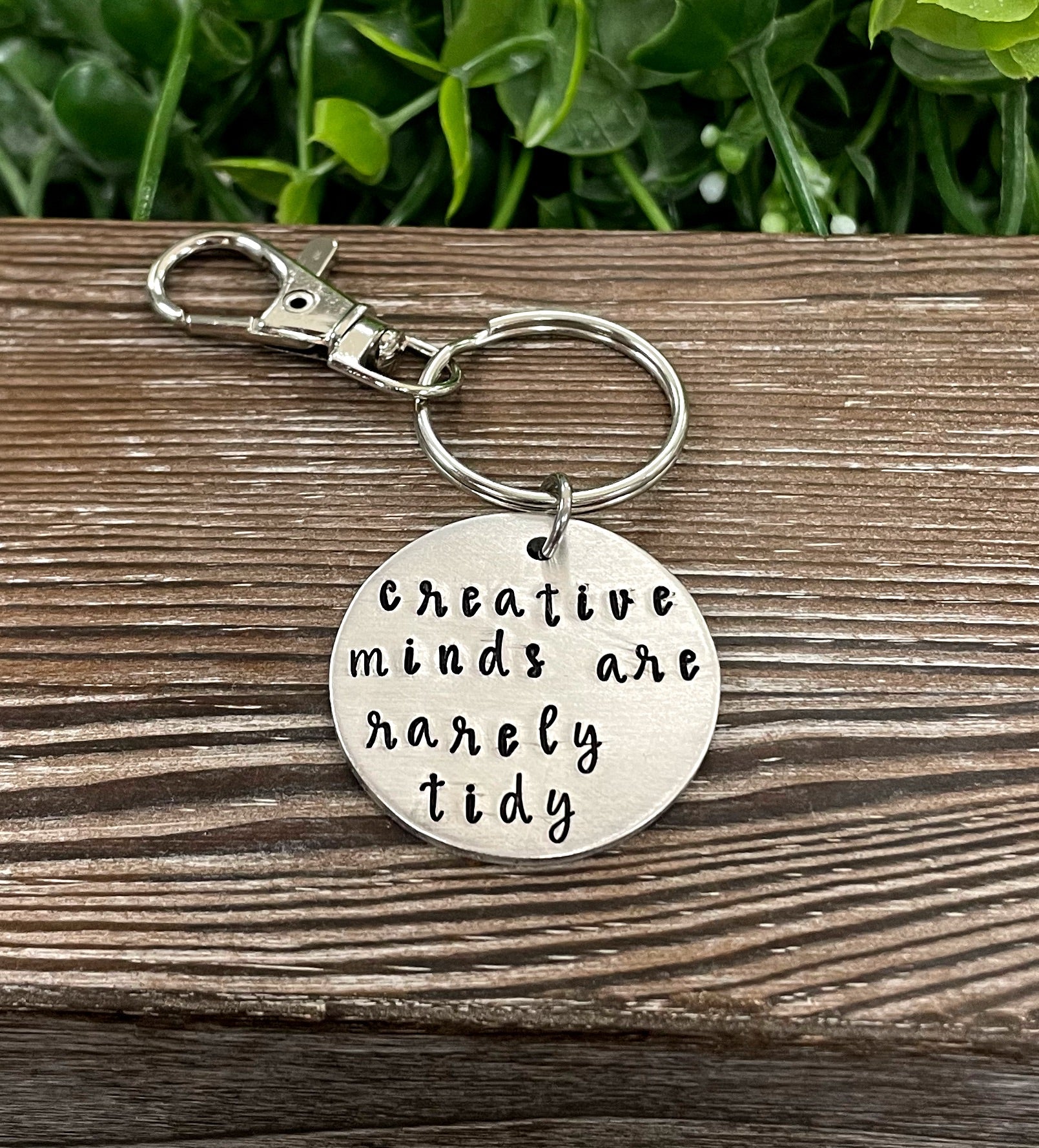 Hand stamped key chain featuring the phrase 'Creative minds are rarely tidy', showcasing unique variations in design and craftsmanship.