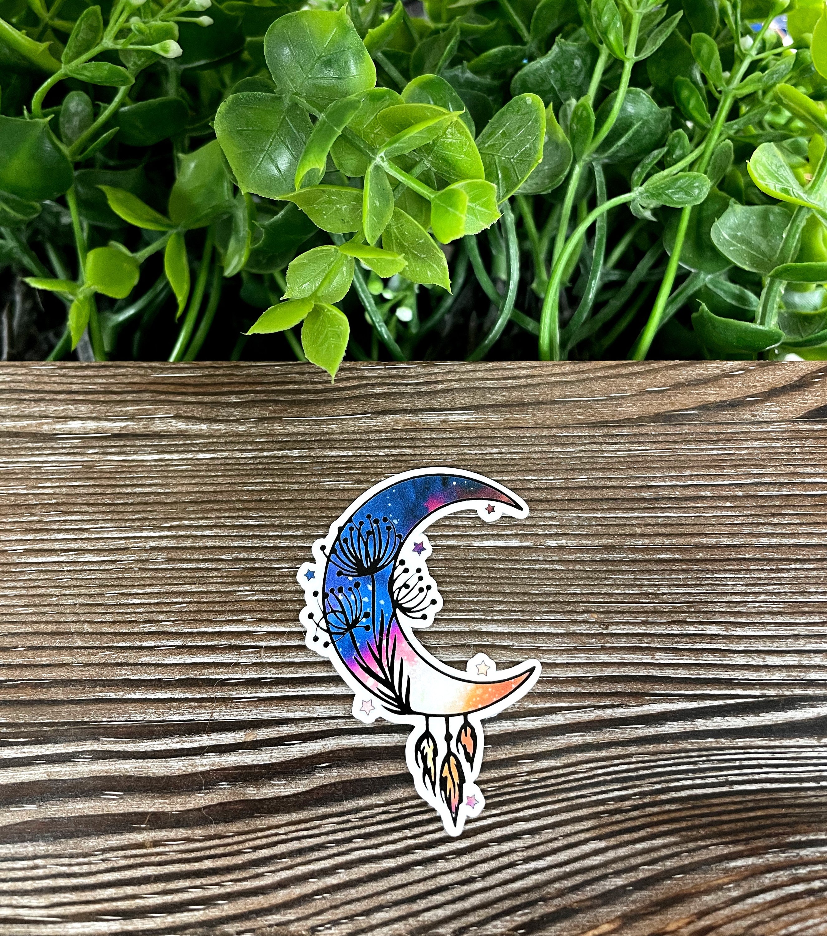 Crescent Moon with Feathers Sticker on a smooth surface, showcasing vibrant colors and intricate design.
