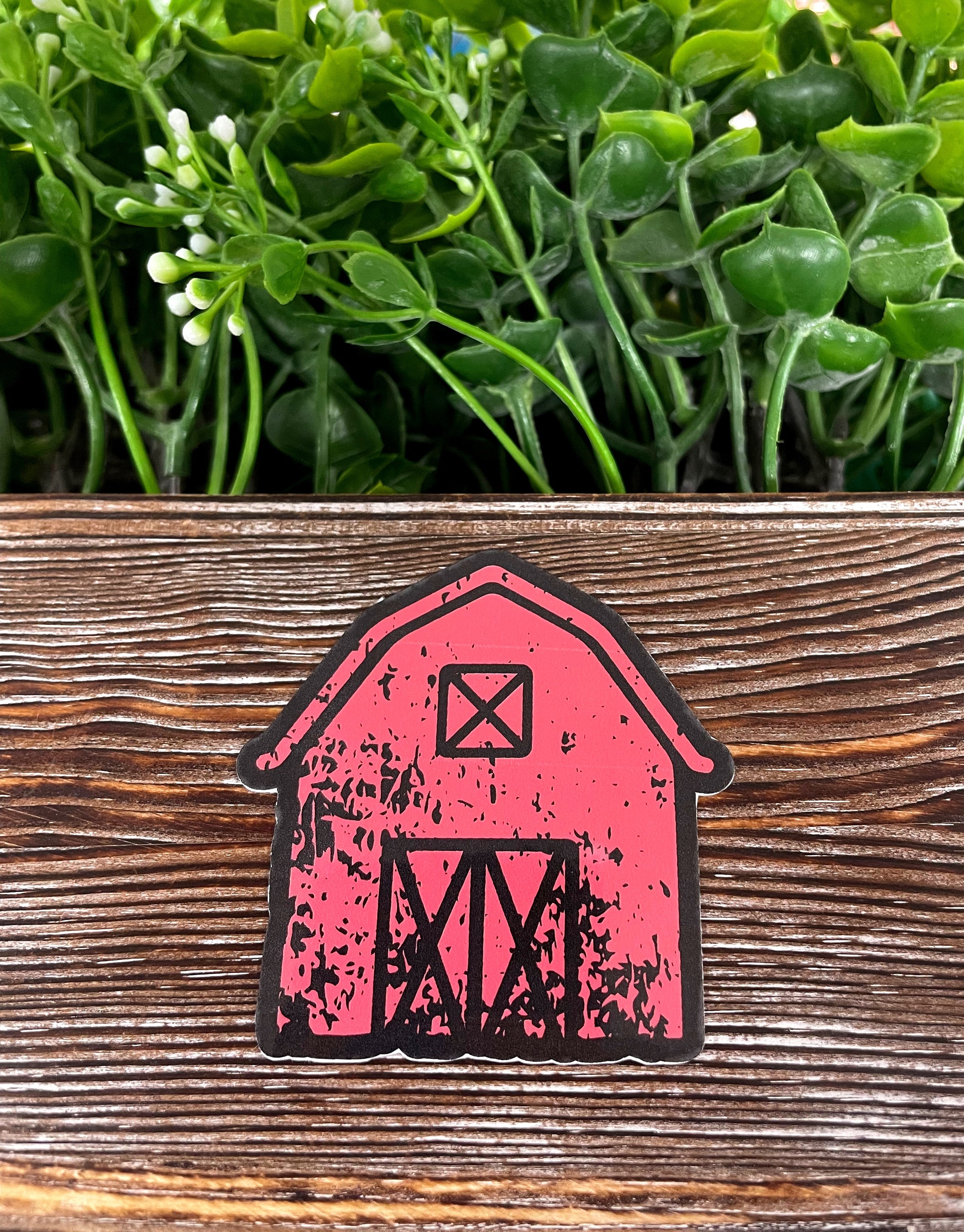 A vibrant Distressed Red Farm Barn die cut vinyl sticker on a smooth surface, showcasing its boho fun design and water-resistant laminate.