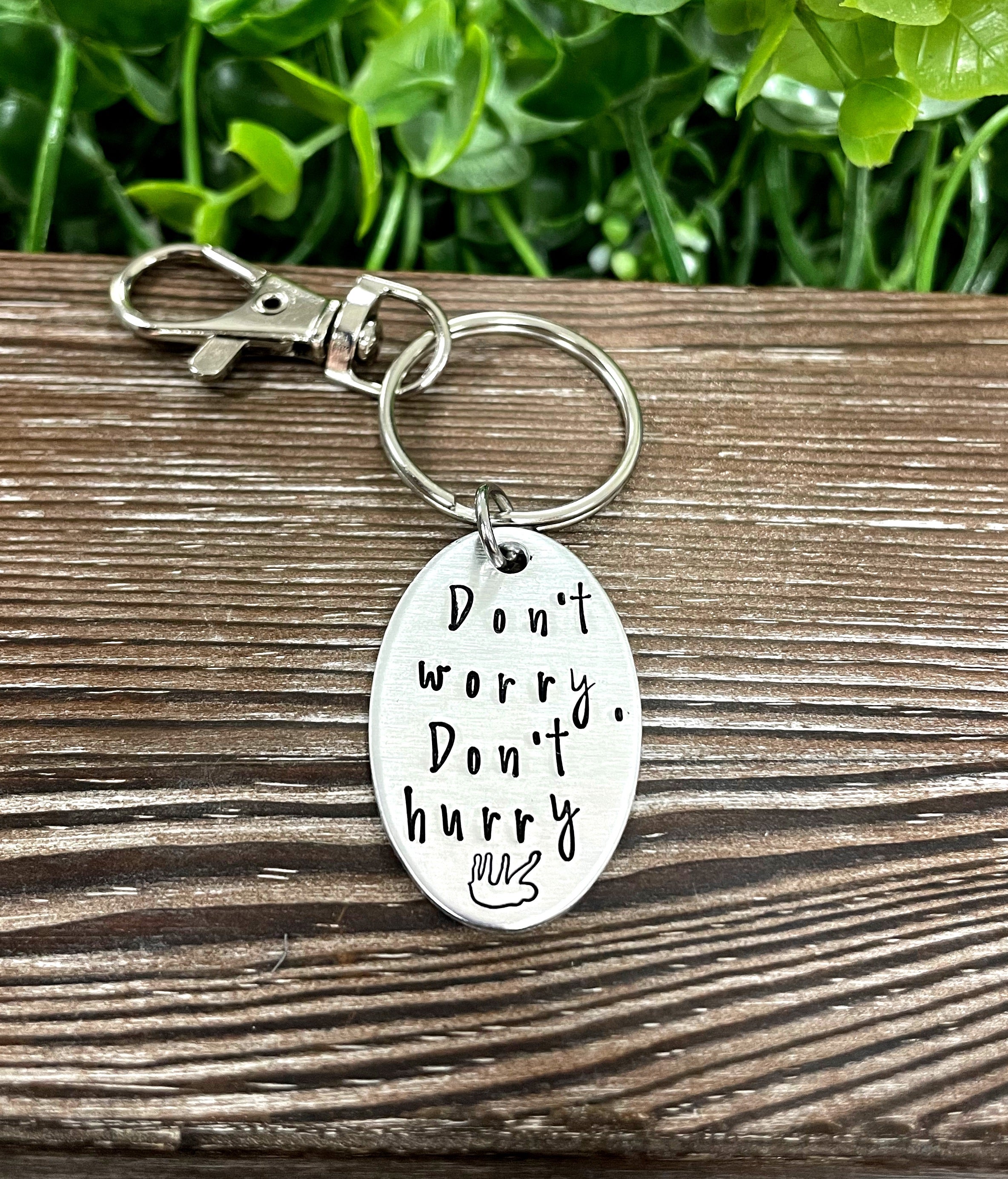 Hand-stamped keychain featuring a sloth design with the phrase 'Don’t Worry, Don’t Hurry', showcasing unique craftsmanship.