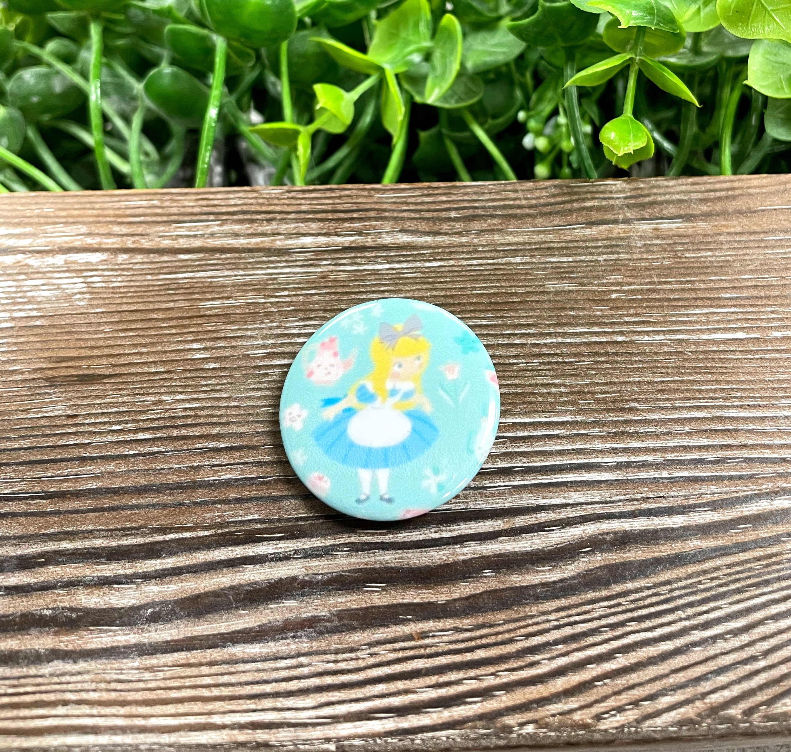 A colorful 1.25-inch graphic art button featuring a fairy tale character design, perfect for personalizing bags and accessories.