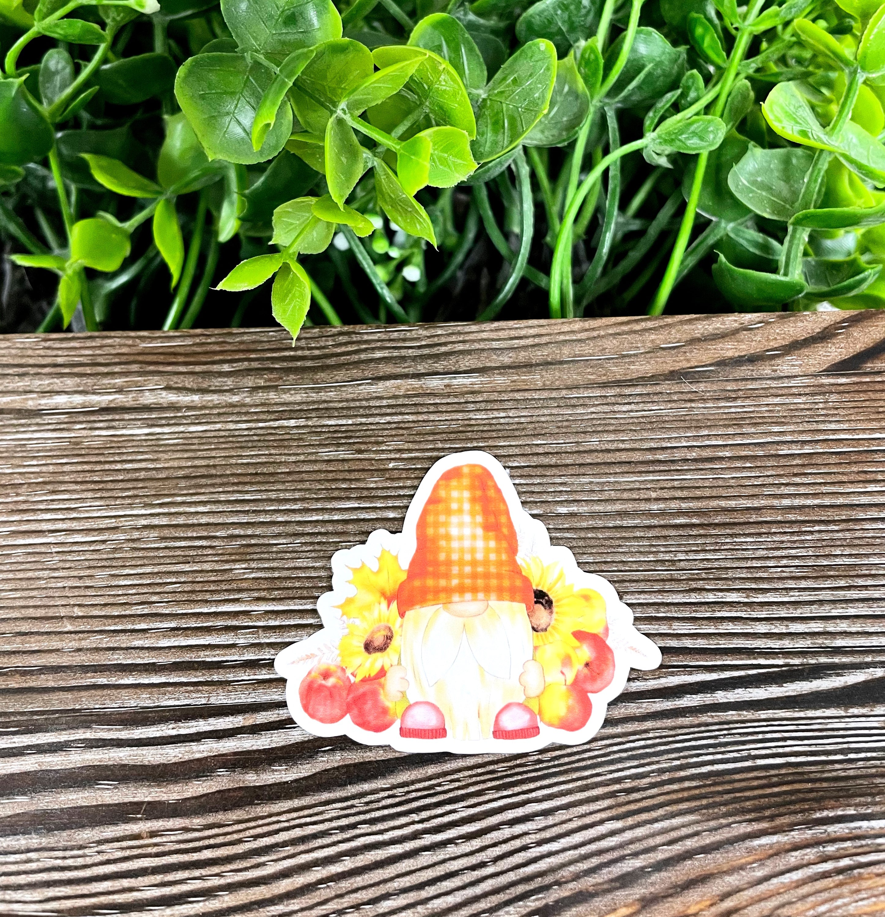 A colorful die cut vinyl sticker featuring a whimsical fall gnome with apples, perfect for personalizing various surfaces.