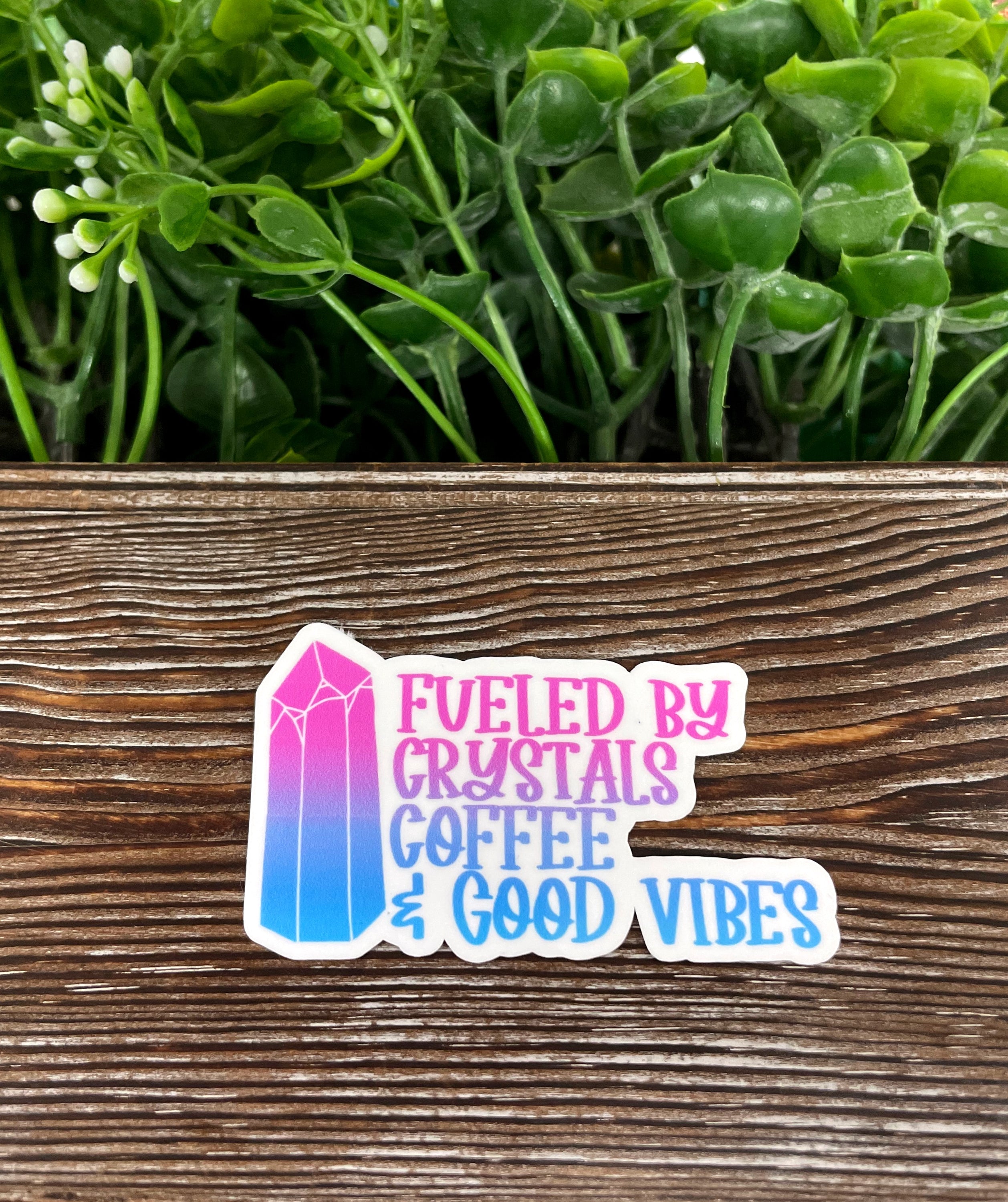 A vibrant die cut vinyl sticker featuring the phrase 'Fueled by Crystals Coffee and Good Vibes' with a boho design, perfect for personalizing items.