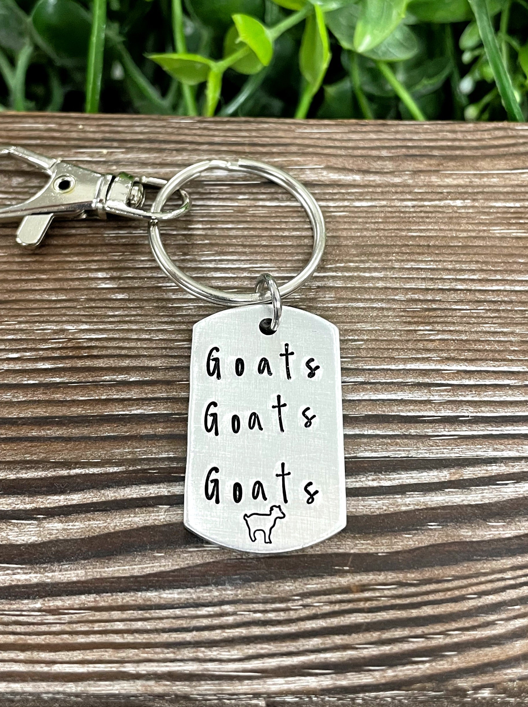 Hand-stamped key chain featuring the phrase 'Goats Goats Goats' with a playful goat design, showcasing unique craftsmanship.