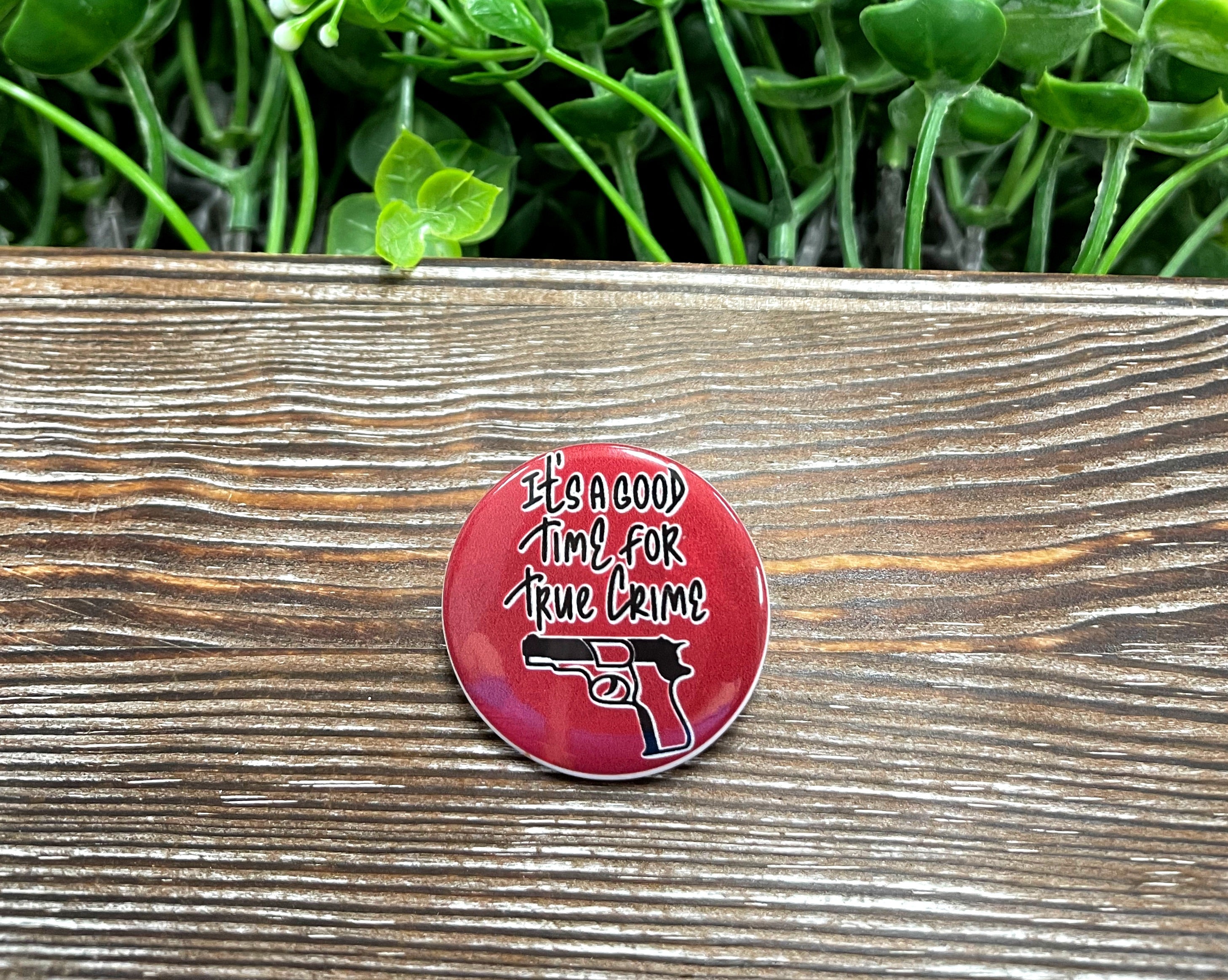 A stylish 1.25-inch graphic art button featuring true crime themes, perfect for accessorizing bags and masks.