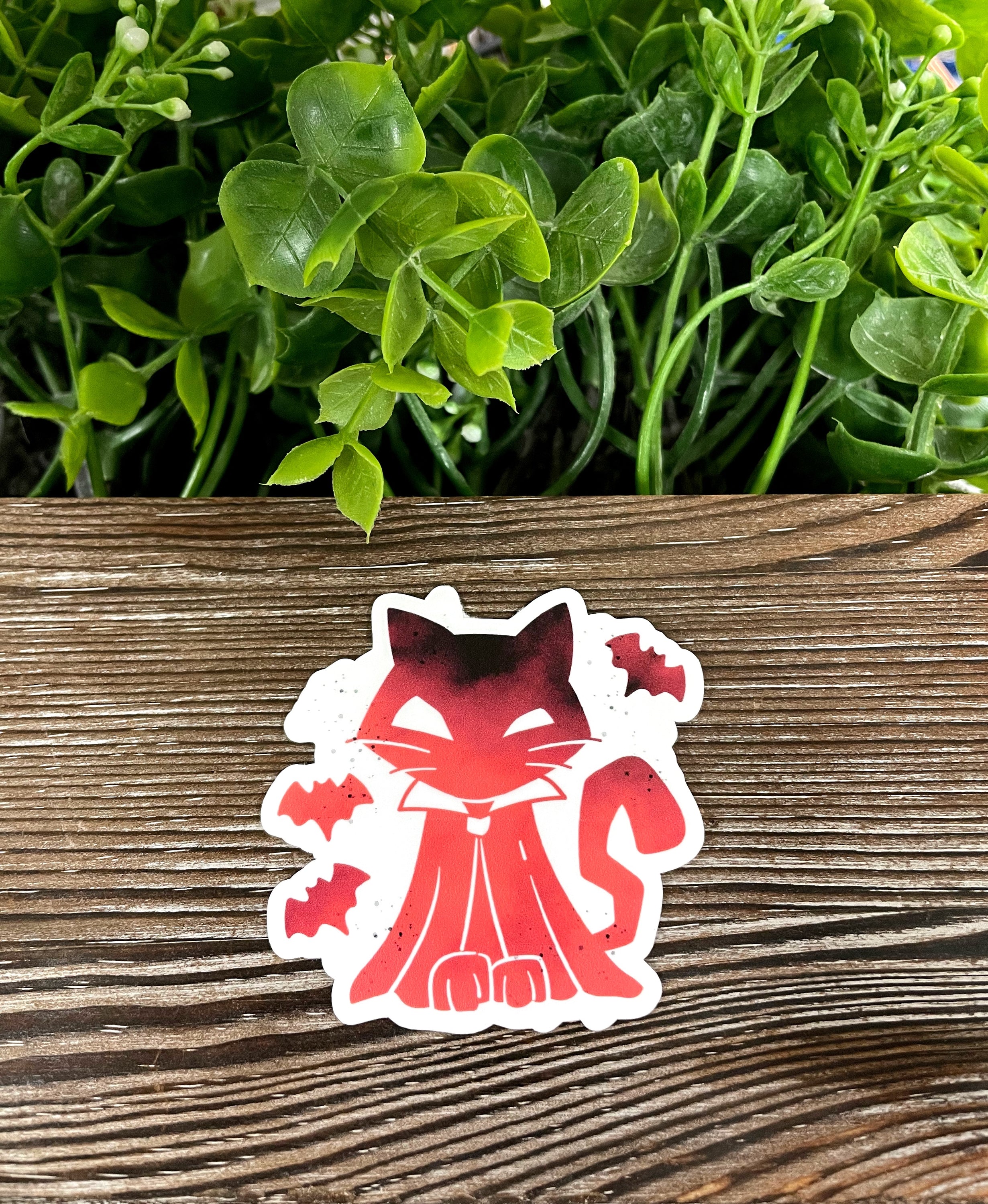 A vibrant die cut vinyl sticker featuring an orange cat surrounded by playful bats, perfect for Halloween decoration.