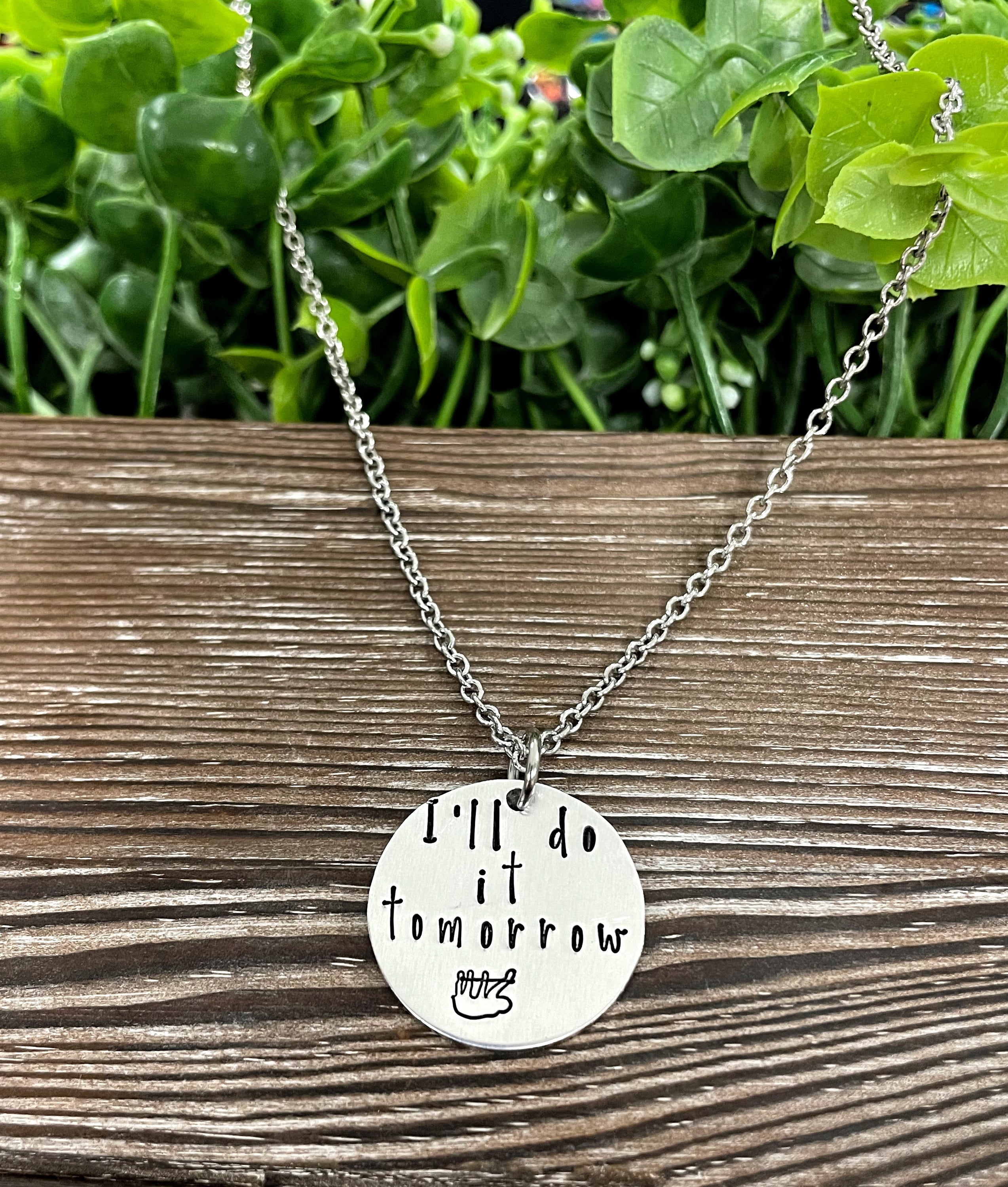 Hand-stamped sloth necklace with the phrase 'I’ll do it Tomorrow', showcasing unique letter variations.