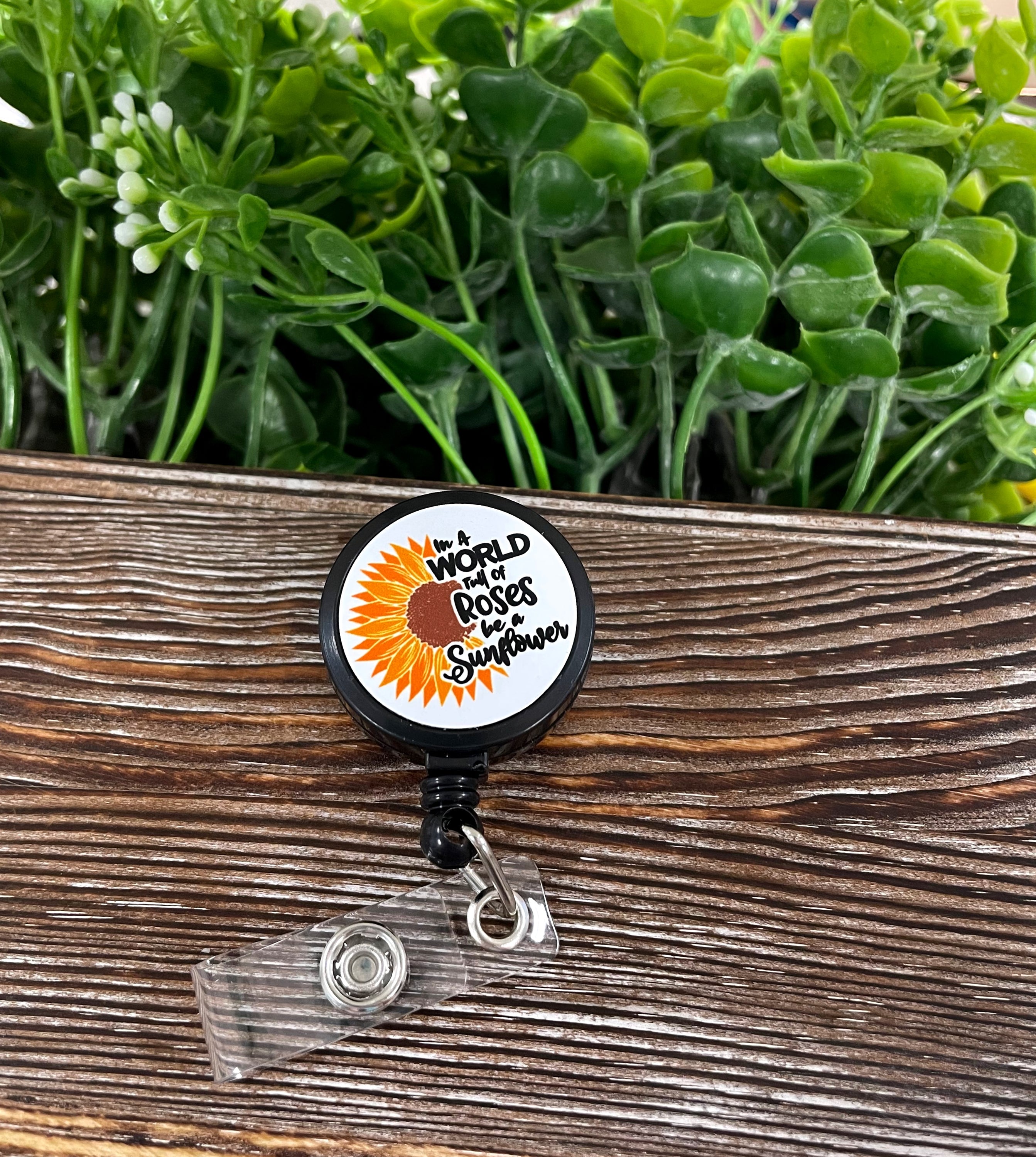 Retractable badge reel featuring a sunflower design on a metal blank, attached to a plastic reel with a 24-inch extension cord.