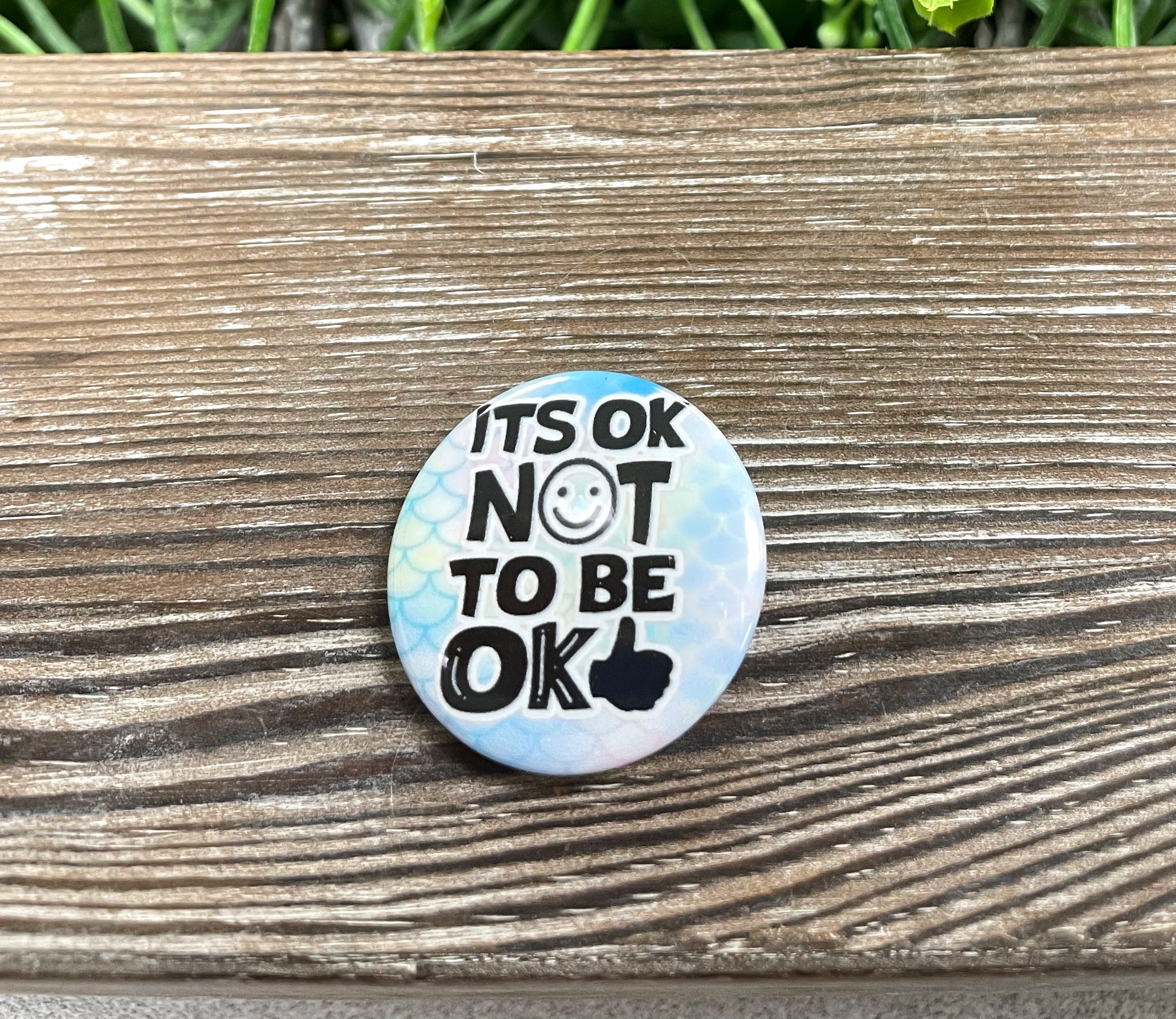 A colorful 1.25-inch button featuring the phrase 'It's OK Not to Be OK' with a vibrant graphic design, suitable for bags and masks.