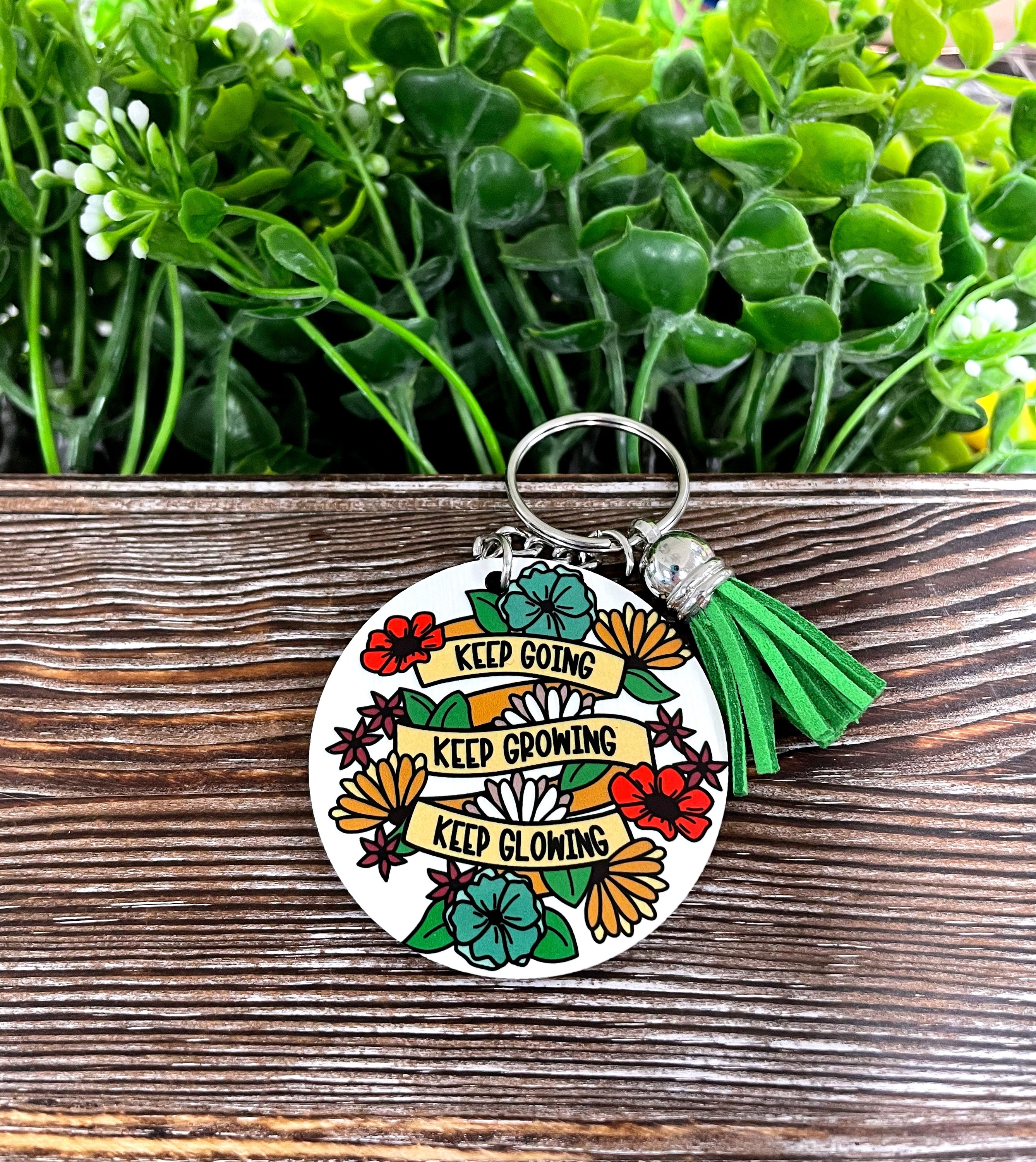A colorful MDF round keychain featuring the phrase 'Keep Going Keep Growing Keep Glowing', showcasing a boho-inspired design.