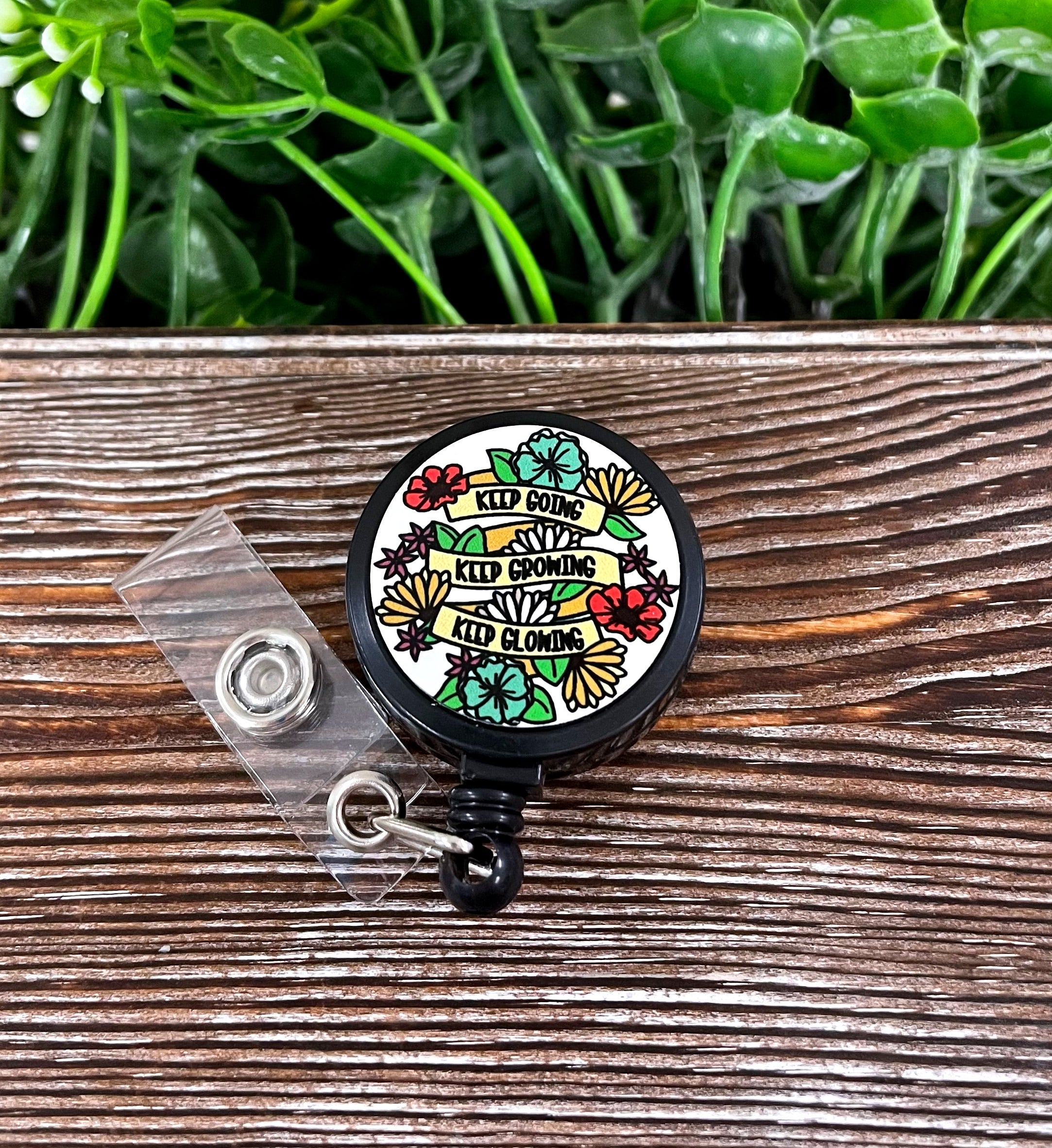 Retractable badge reel featuring a boho design with the phrase 'Keep Going Keep Growing Keep Glowing', attached to a plastic cord.