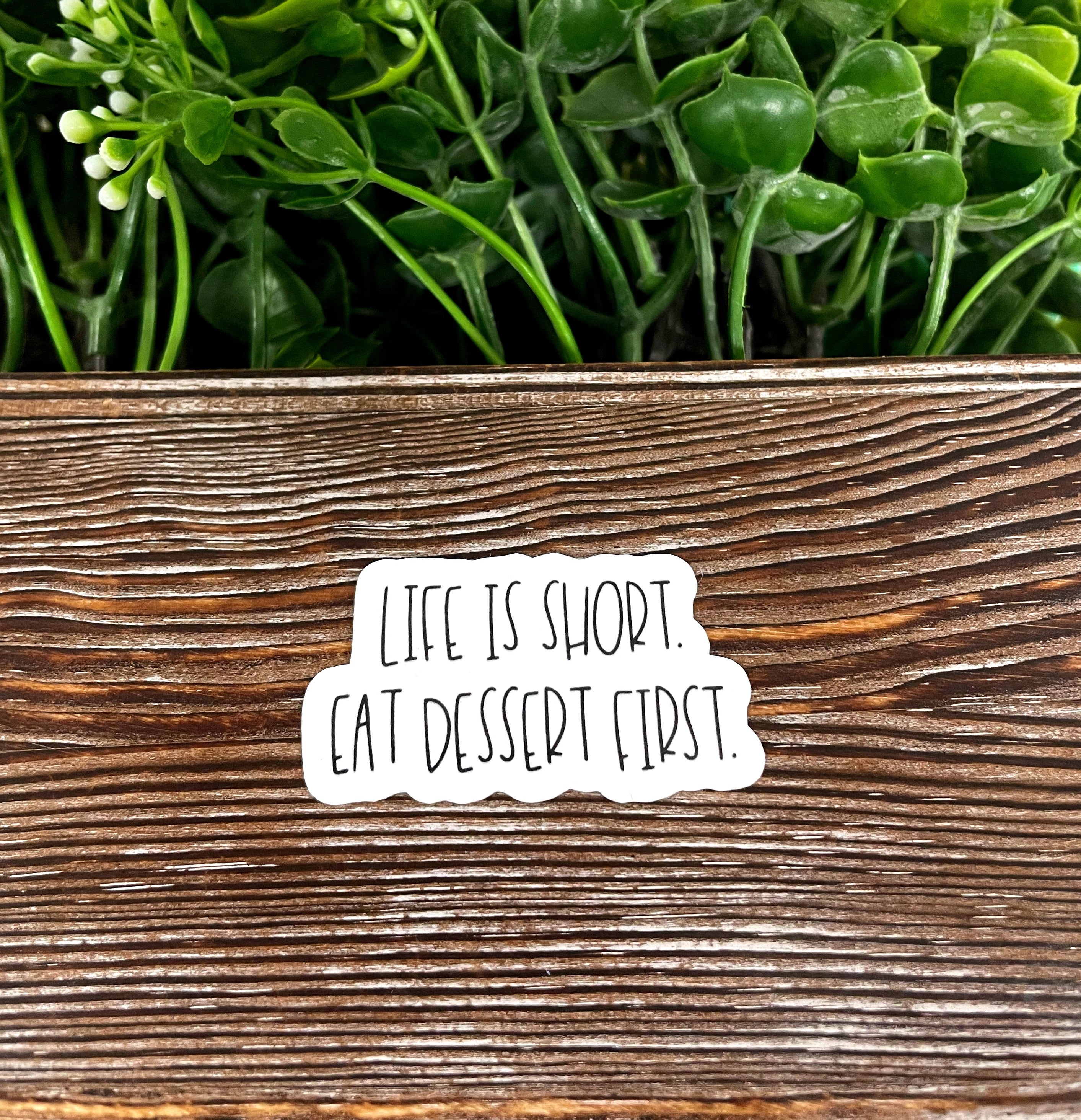 Colorful die cut sticker featuring the phrase 'Life is Short Eat Dessert First' on a smooth surface, showcasing its vibrant design.