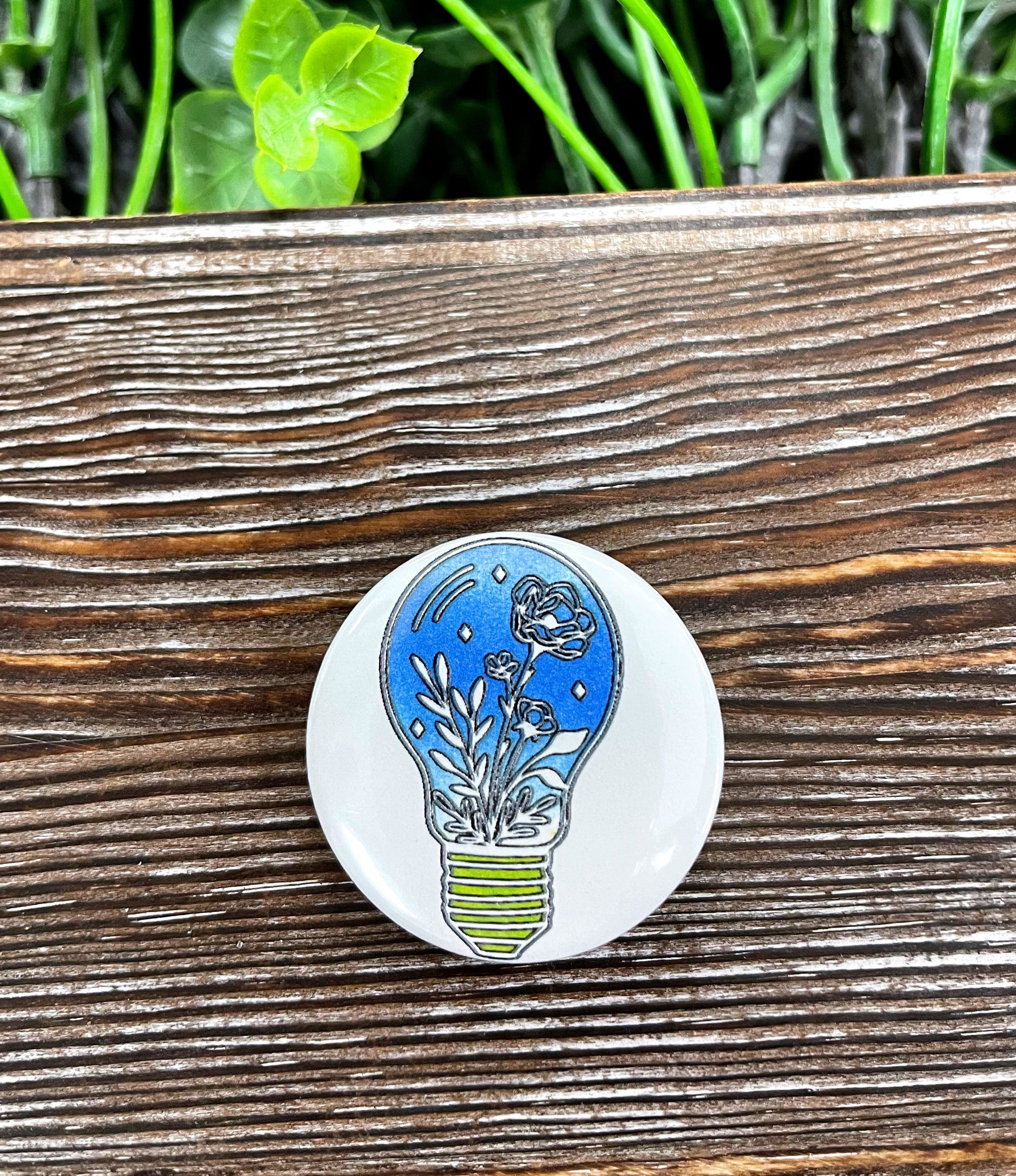 A colorful 1.25-inch button featuring a lightbulb flowers graphic design, perfect for personalizing bags and accessories.