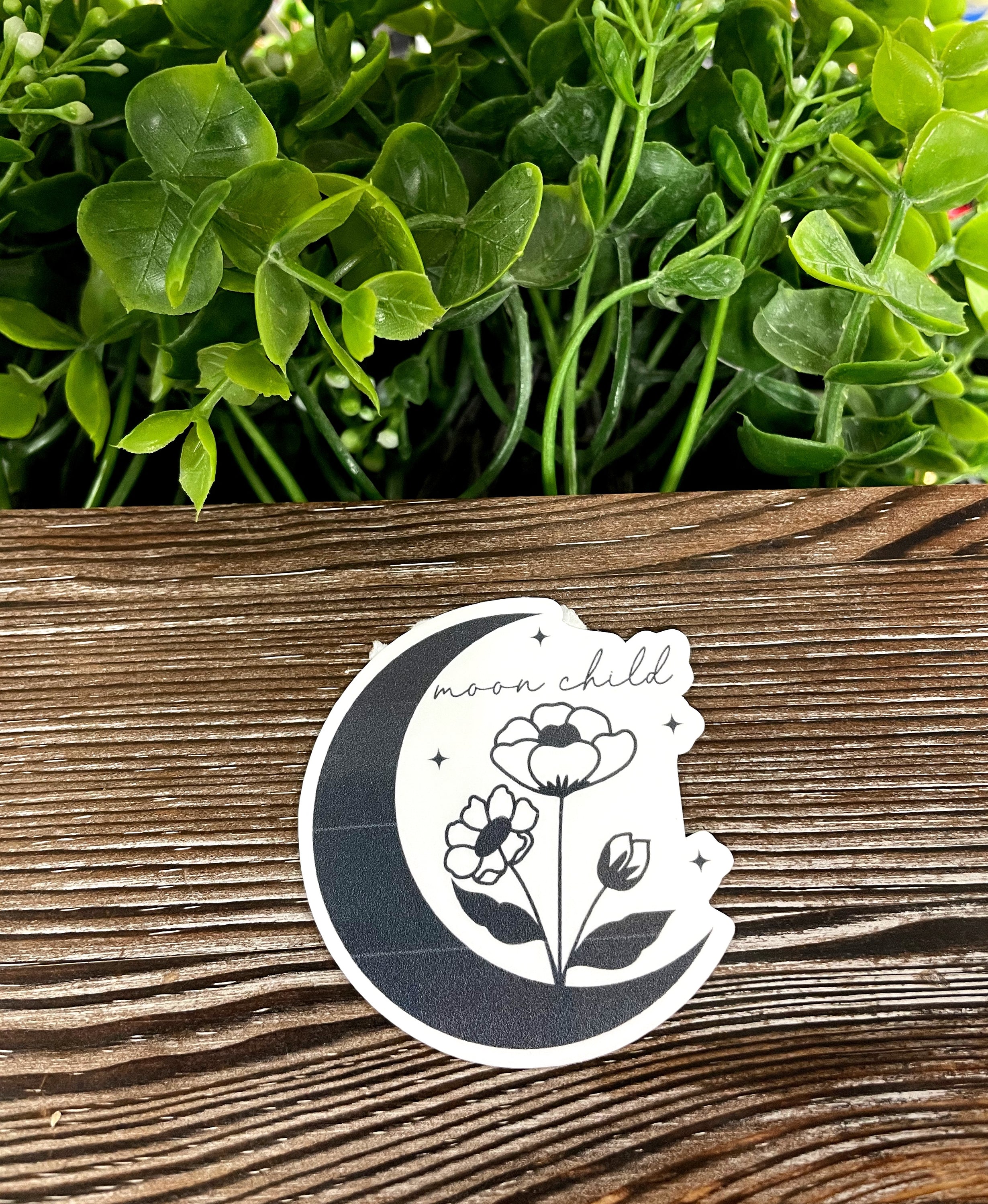 Moon Child die cut vinyl sticker featuring a crescent moon and flowers, perfect for personalizing various surfaces.