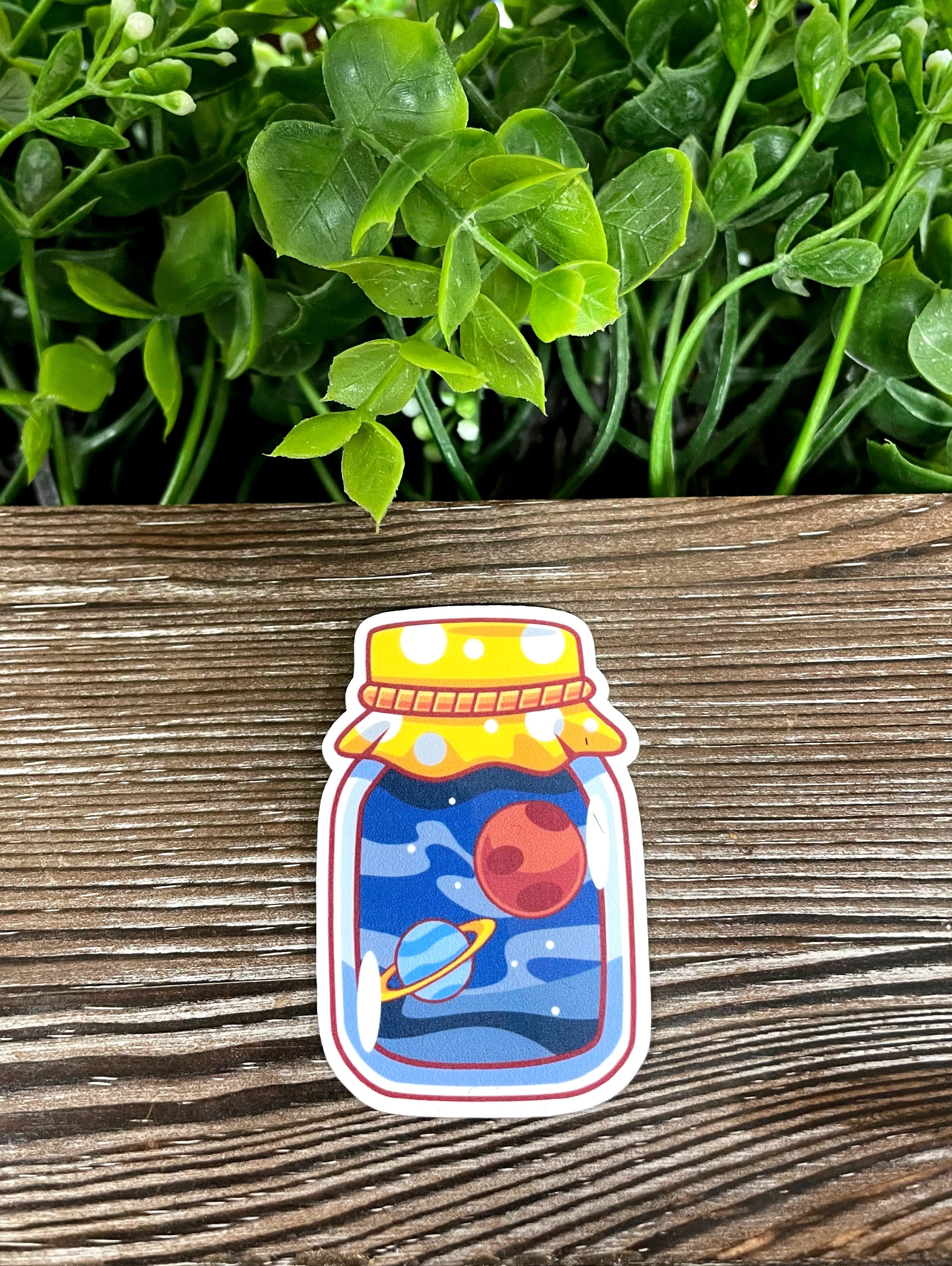 Die cut vinyl sticker featuring outer space in a mason jar design, showcasing vibrant colors and a boho aesthetic.