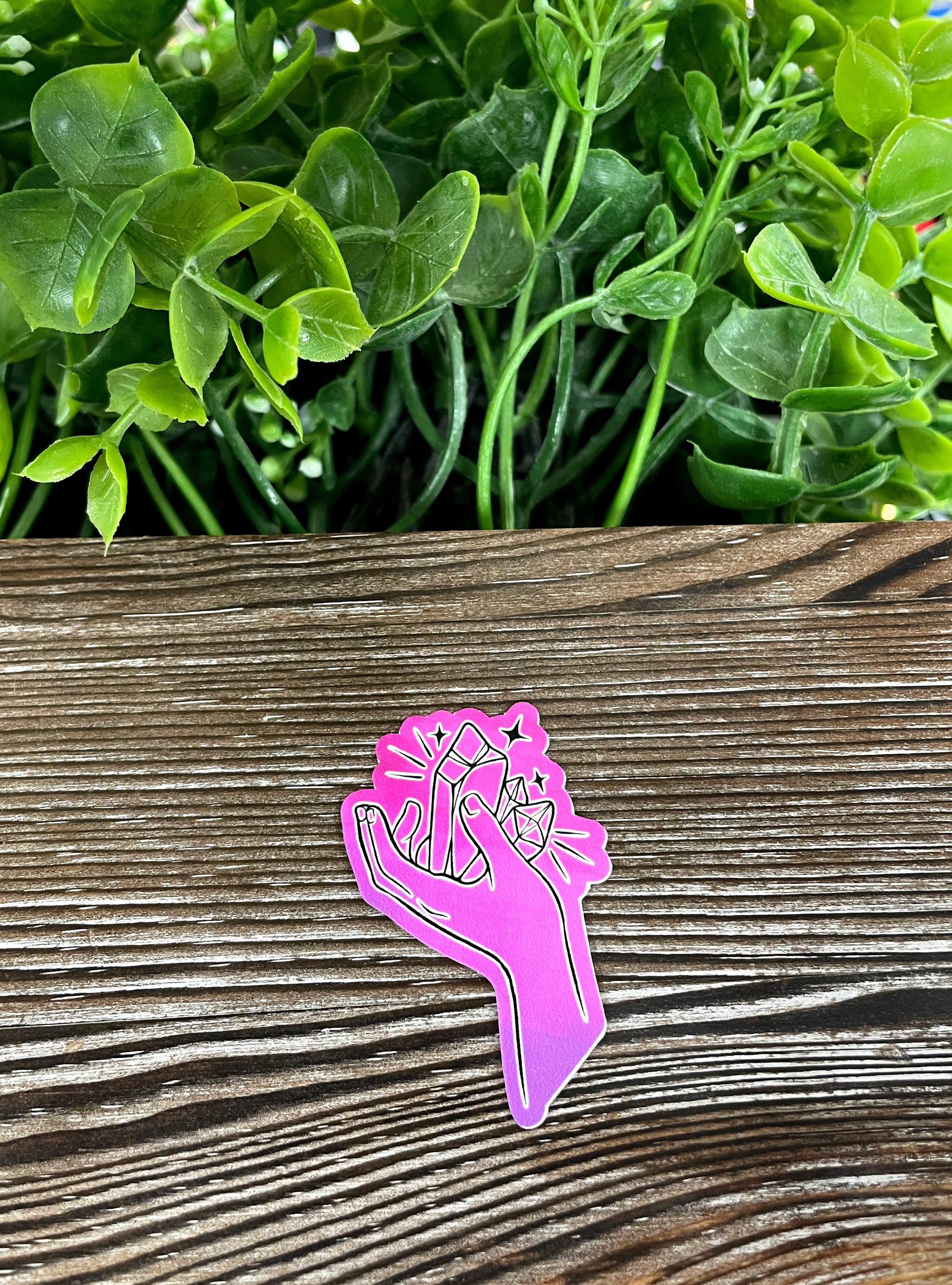 A vibrant purple hand holding colorful crystal gems, designed as a die cut vinyl sticker, showcasing a boho aesthetic.