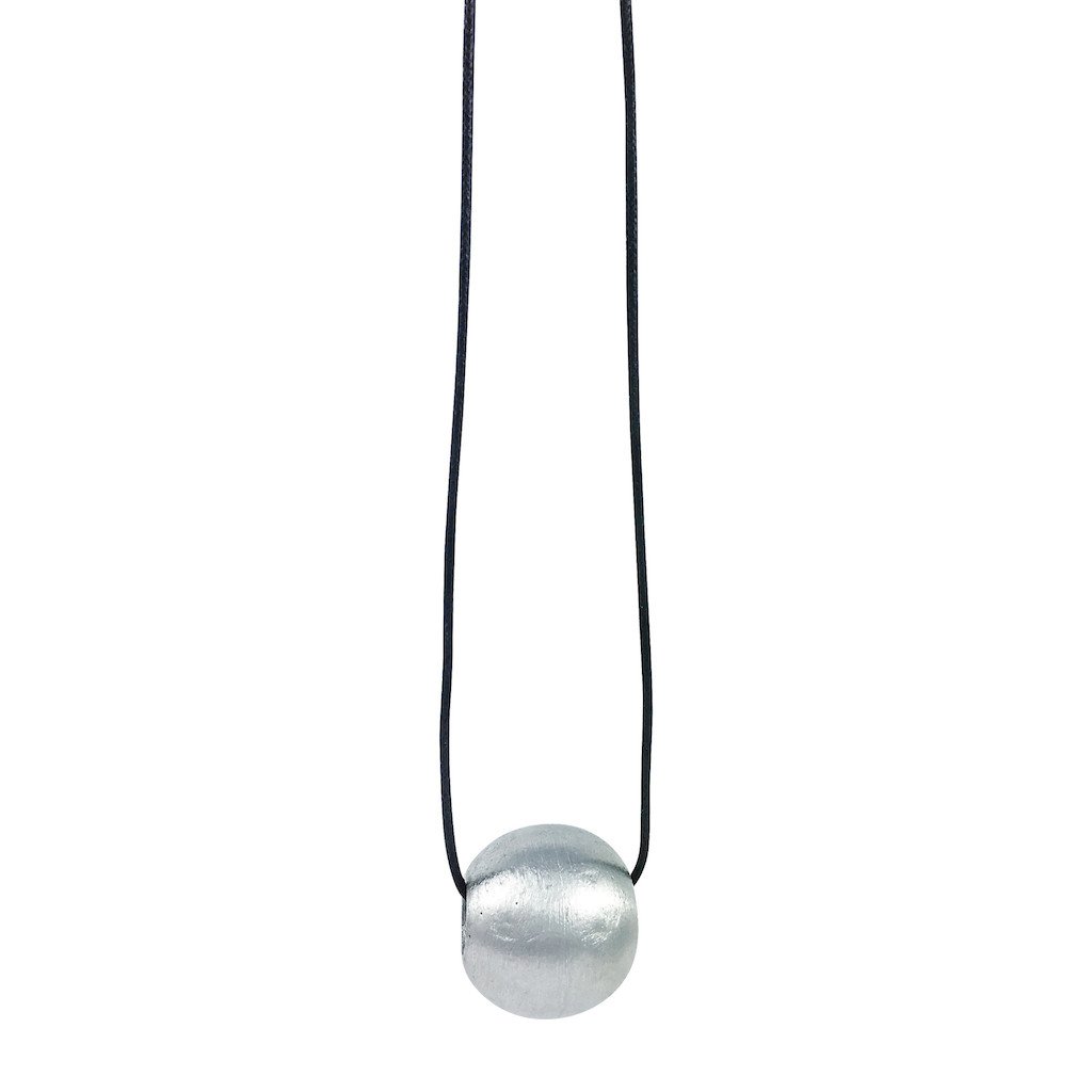 Recycled Bombshell Ball Necklace featuring a 1-inch pendant made from recycled aluminum bomb parts, displayed on an adjustable cord in olive green, black, or red.