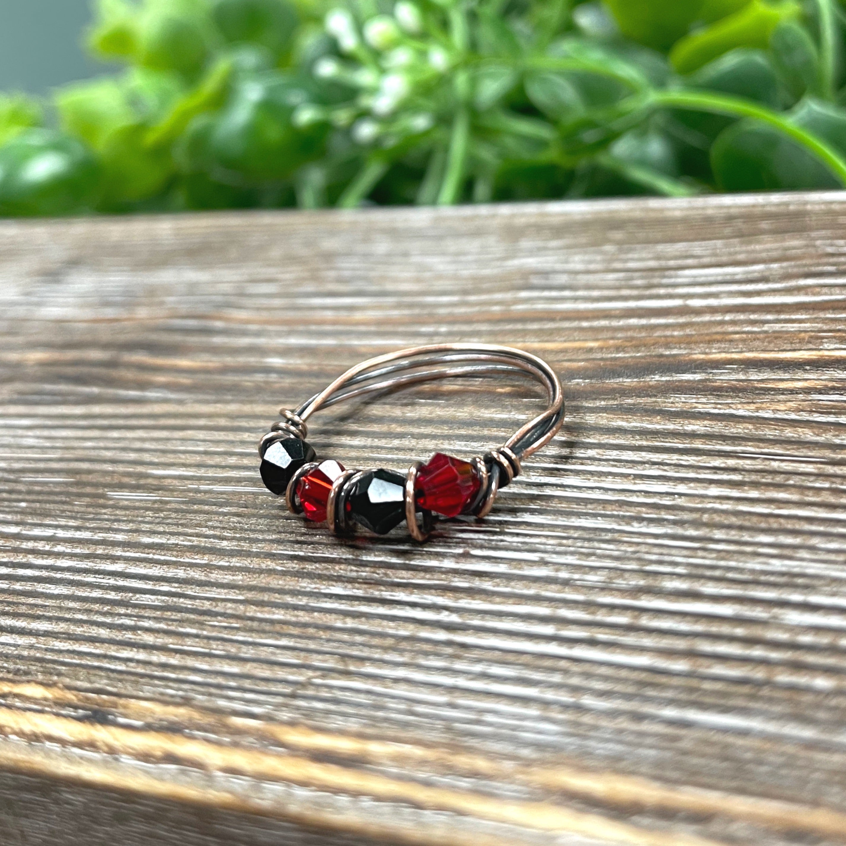 A beautifully crafted Red and Black Glass Crystal Wire Wrapped Ring featuring oxidized copper wire, showcasing vibrant glass beads.