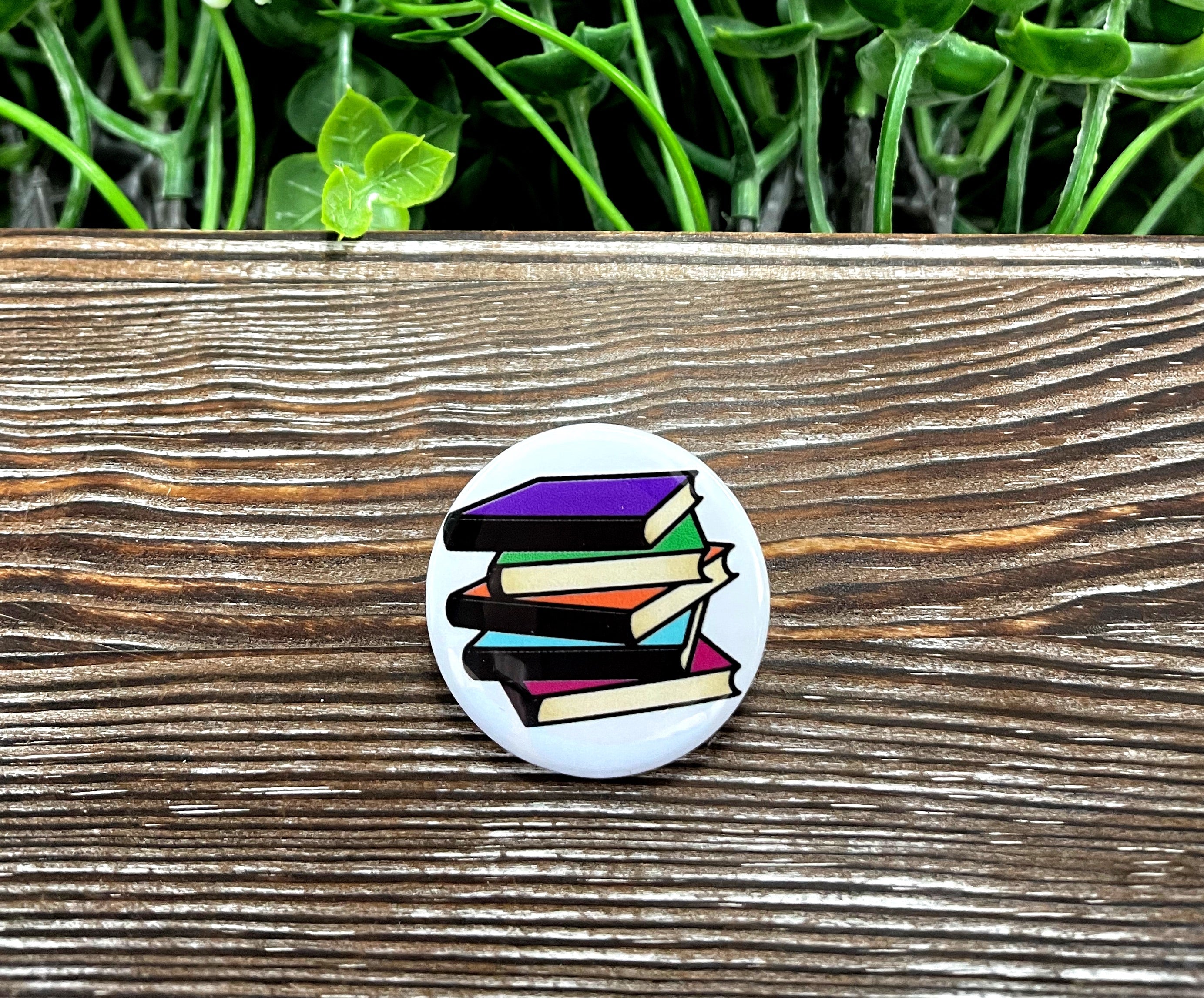 A colorful 1.25-inch button featuring a stack of books design, perfect for book lovers.