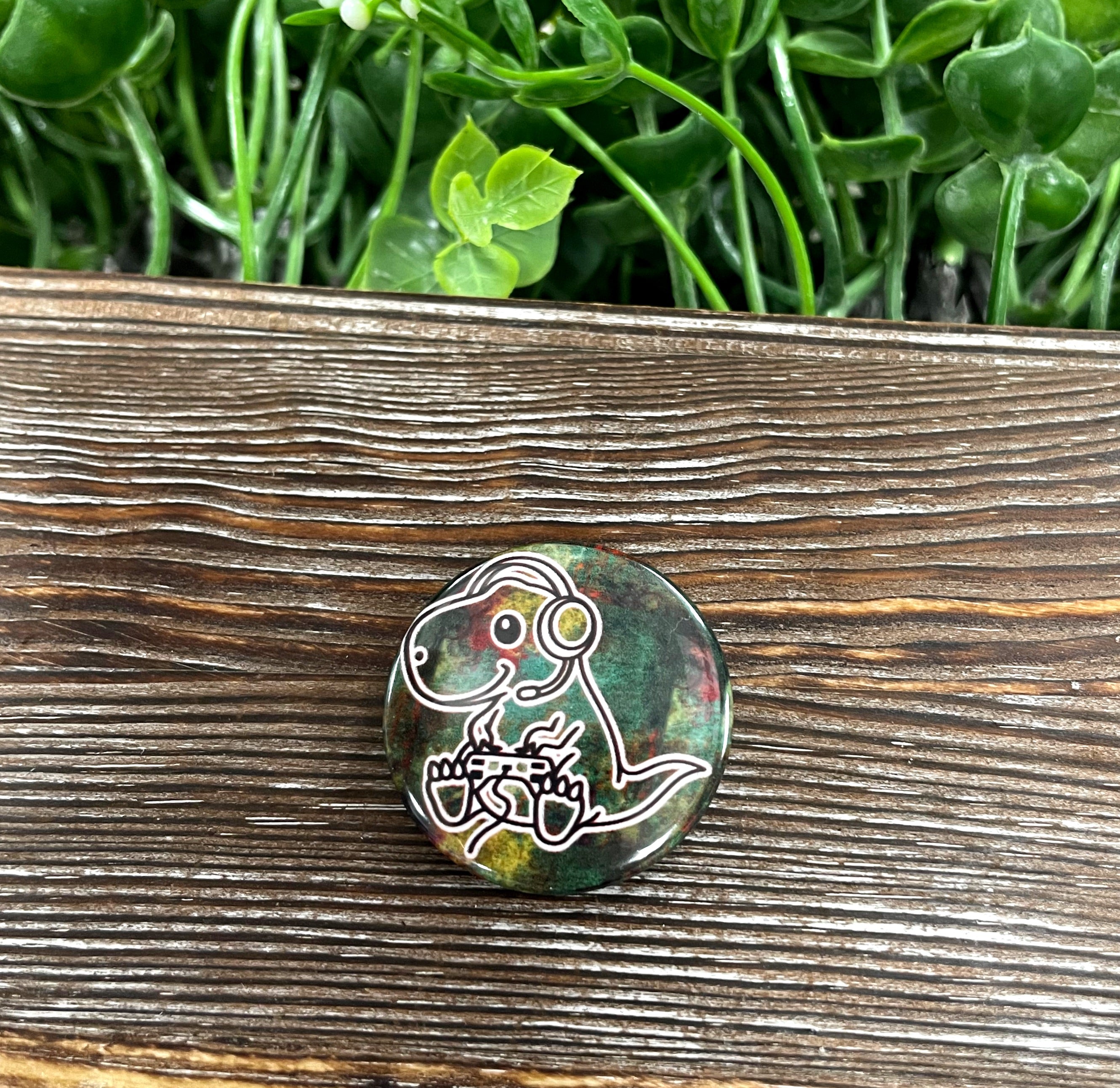 A colorful 1.25-inch T Rex graphic art button, showcasing a playful dinosaur design, perfect for gamers and enthusiasts.