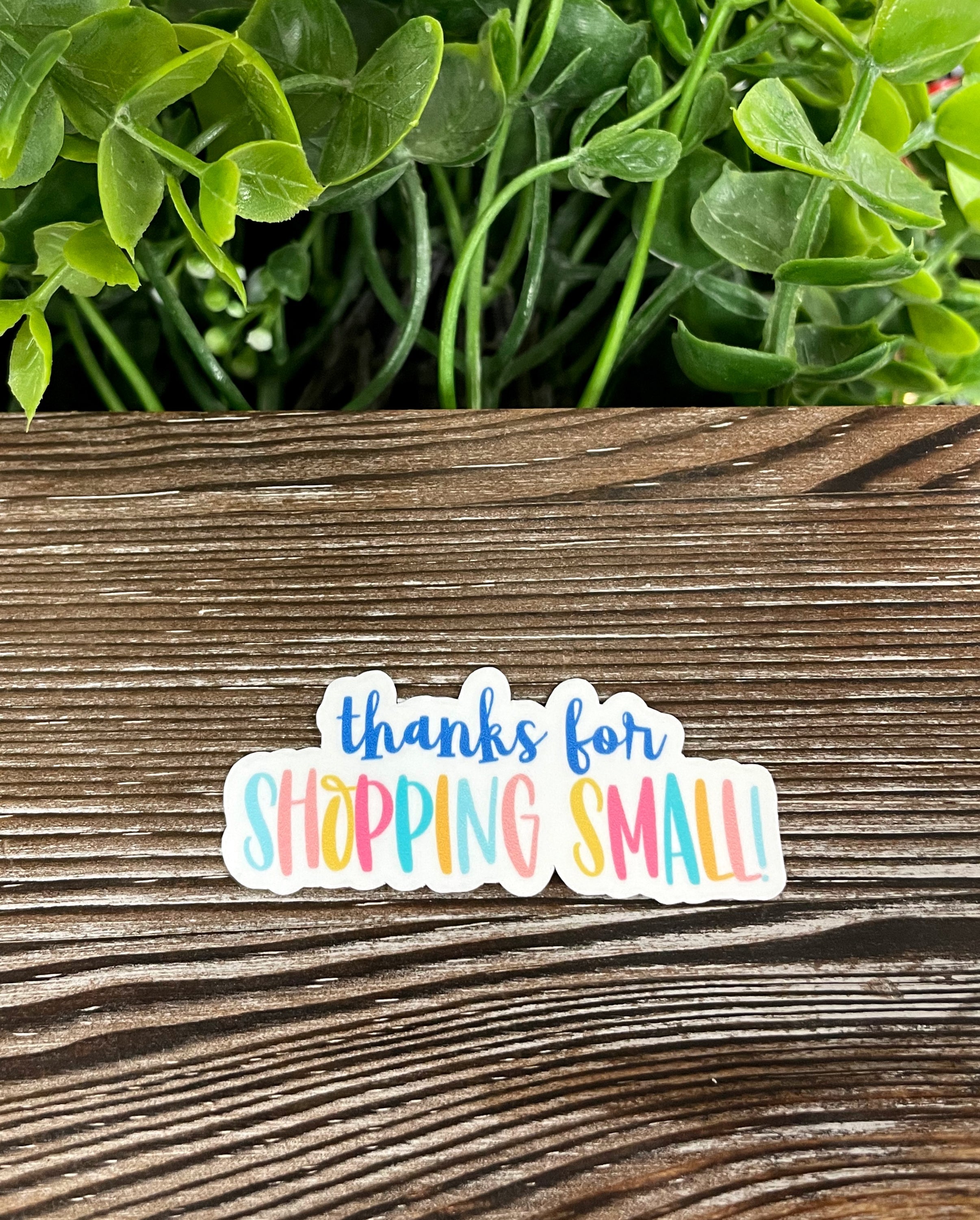 Thanks for Shopping Small die cut vinyl sticker on a smooth surface, showcasing vibrant colors and a stylish design.