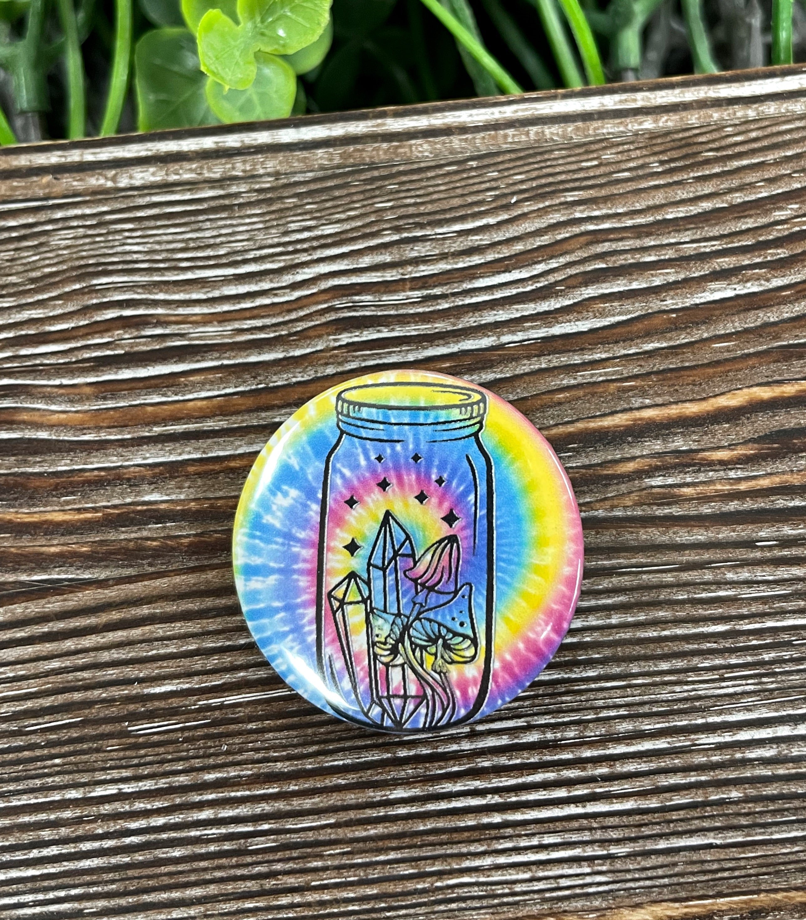 A colorful 1.25-inch tie dye button featuring mushrooms and crystals, perfect for personalizing bags and accessories.