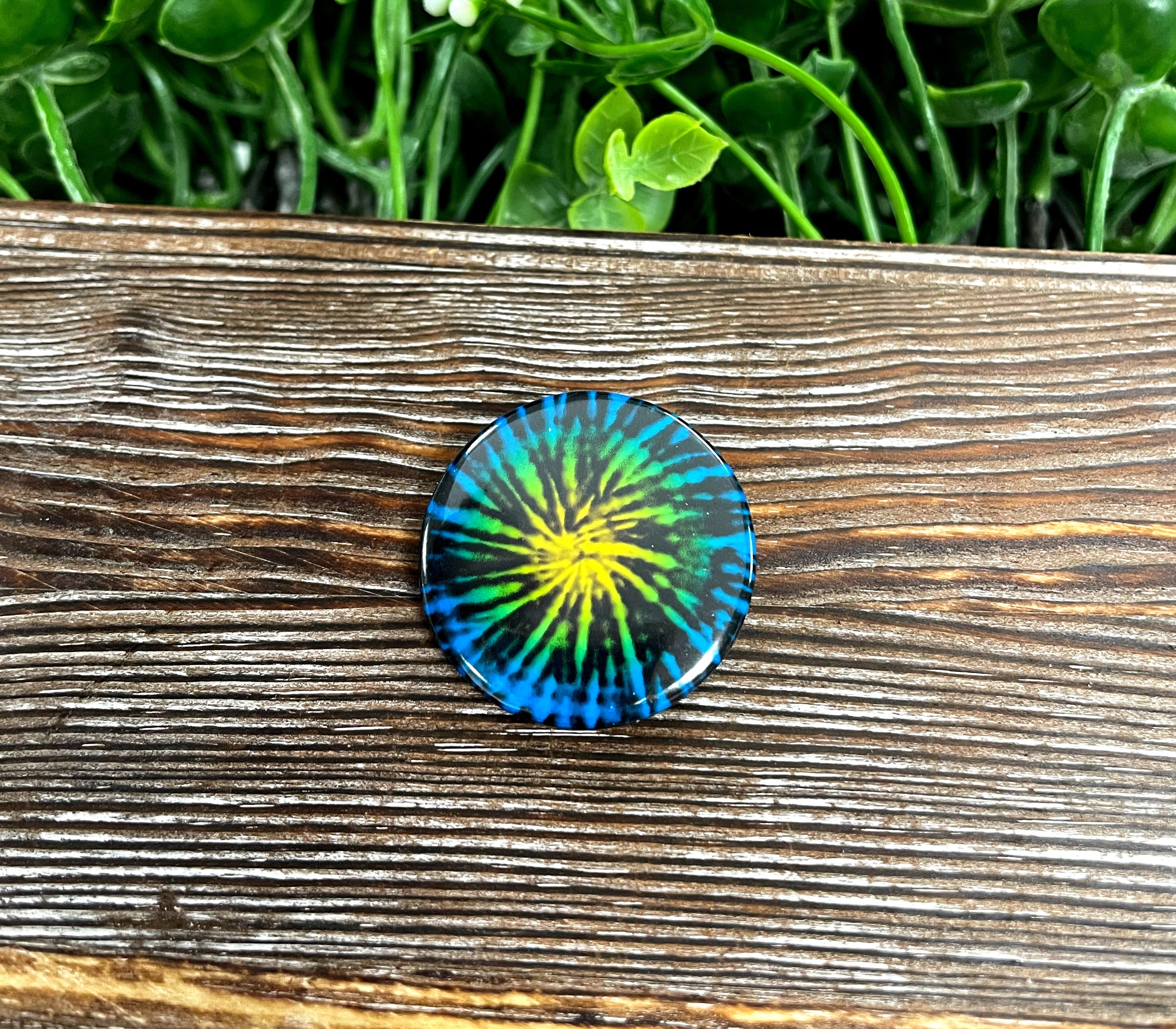 A colorful 1.25-inch tie dye explosion graphic art button with a plastic back, showcasing vibrant colors.