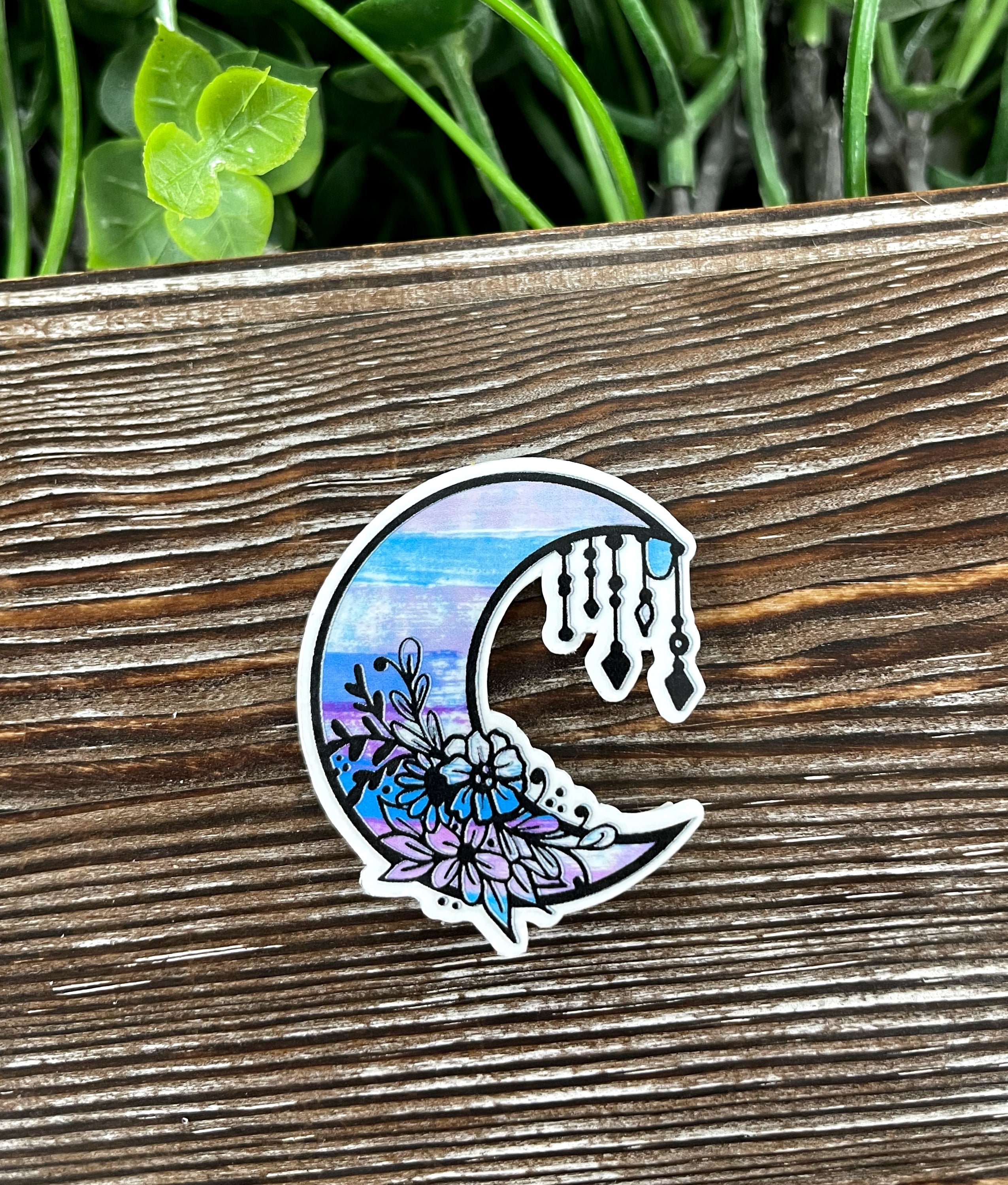 Watercolor Crescent Moon Die Cut Sticker on a smooth surface, showcasing vibrant colors and intricate design.