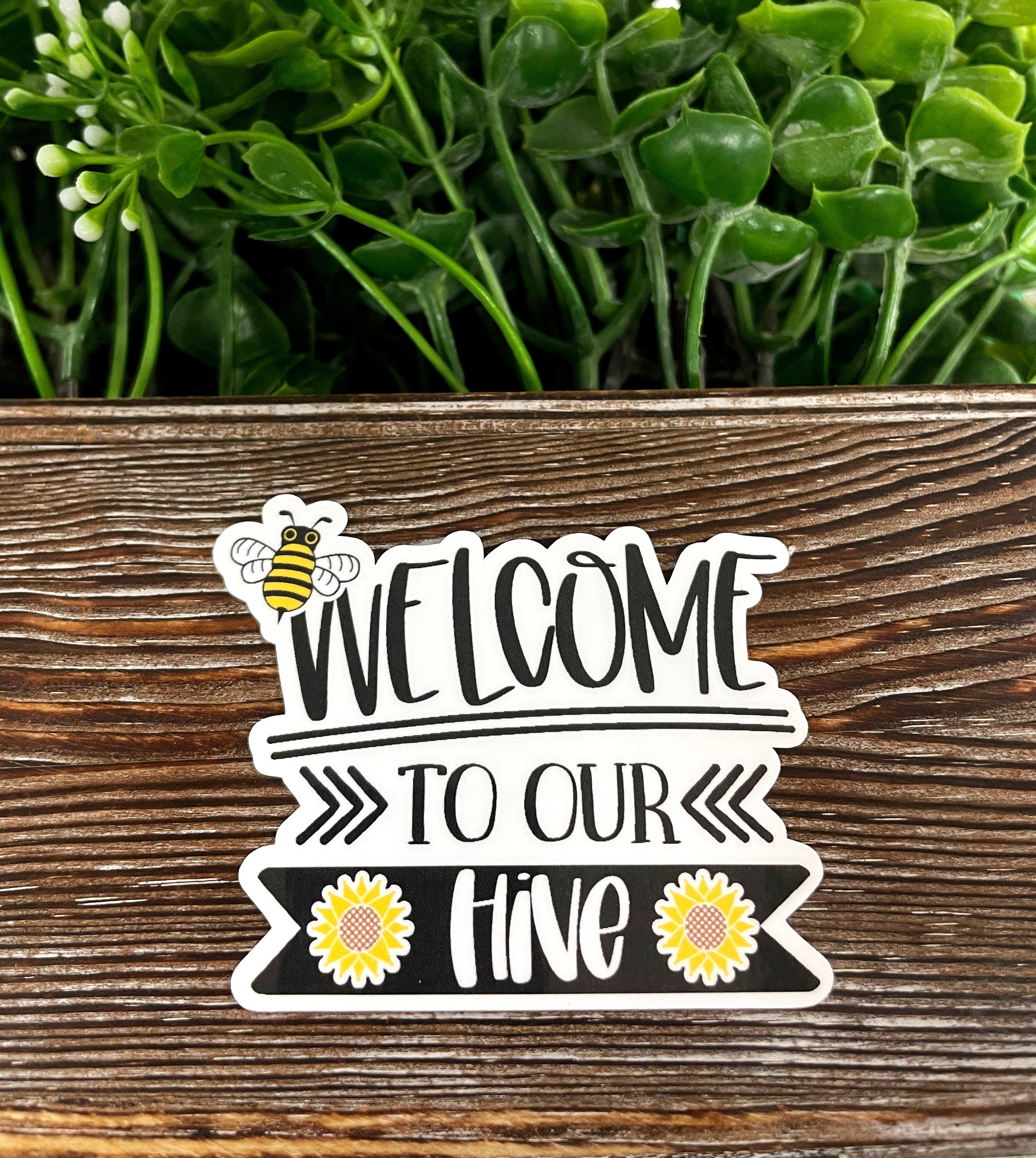 Welcome to Our Hive Bees die cut sticker on a smooth surface, showcasing vibrant colors and intricate design.