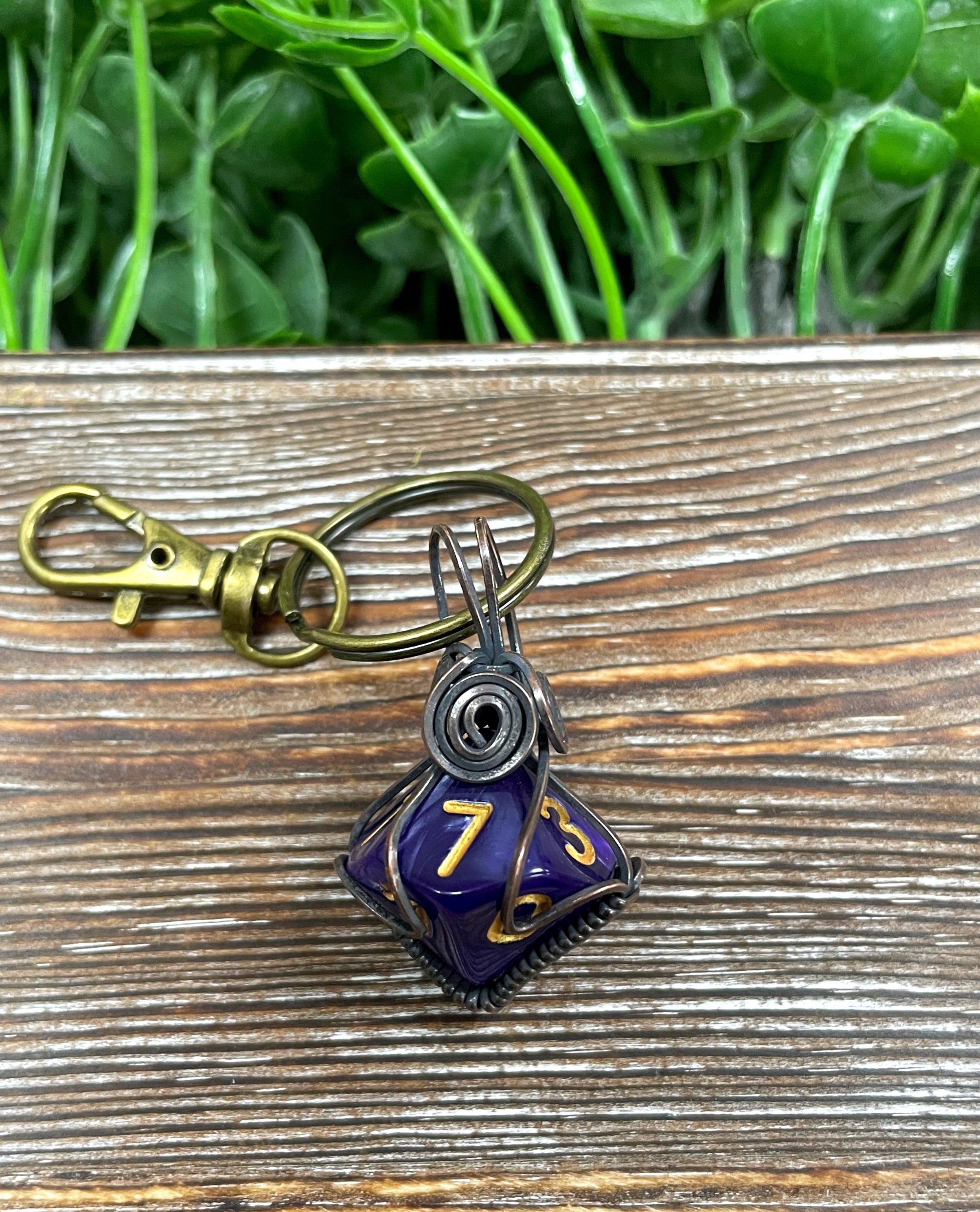 Wire wrapped D10 dice key chain featuring oxidized copper wire and a bronze key chain, showcasing random colors and an antique finish.