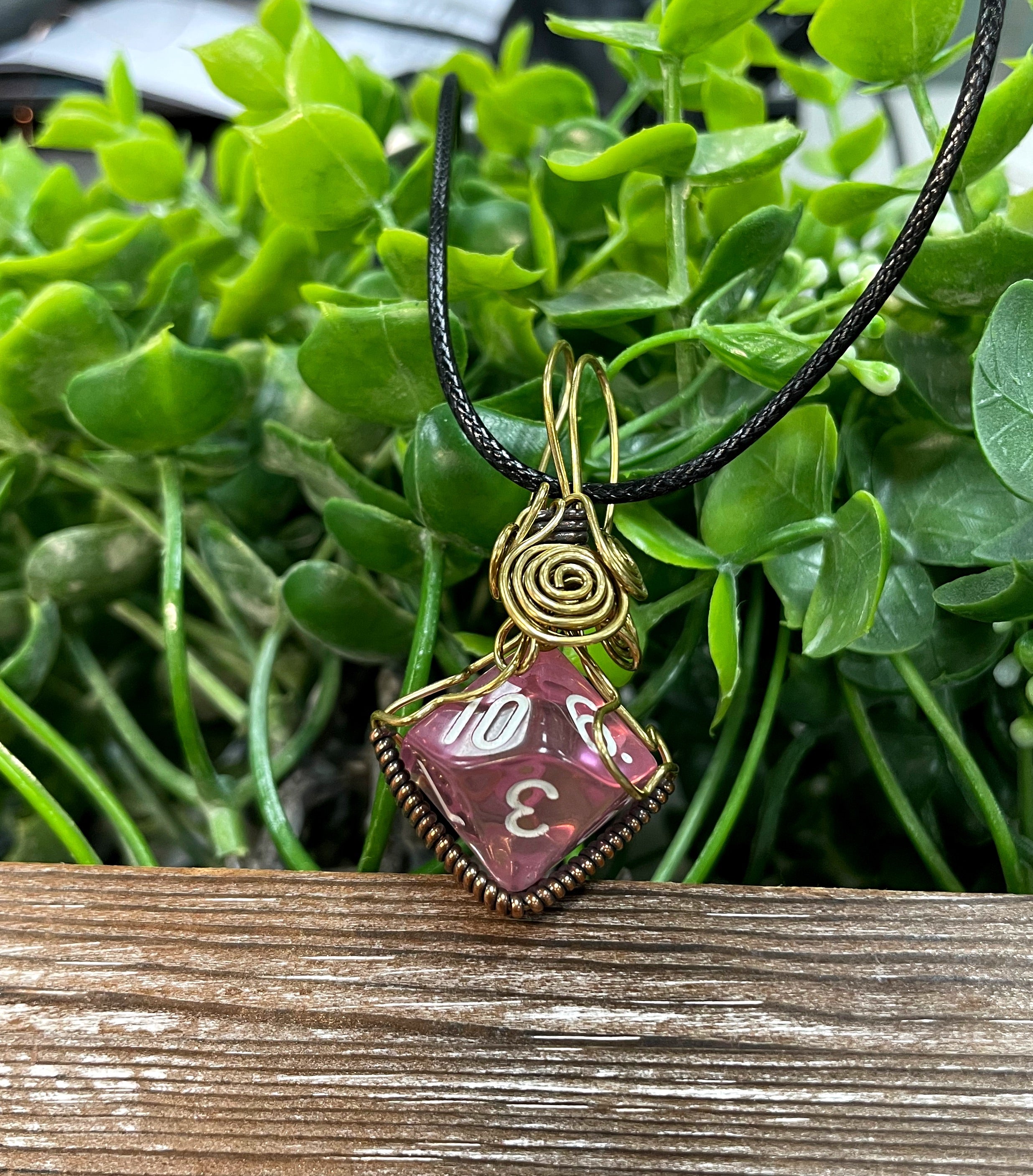 Wire Wrapped D10 Dice Pendant in pink, featuring oxidized copper wire and a suede leather cord.