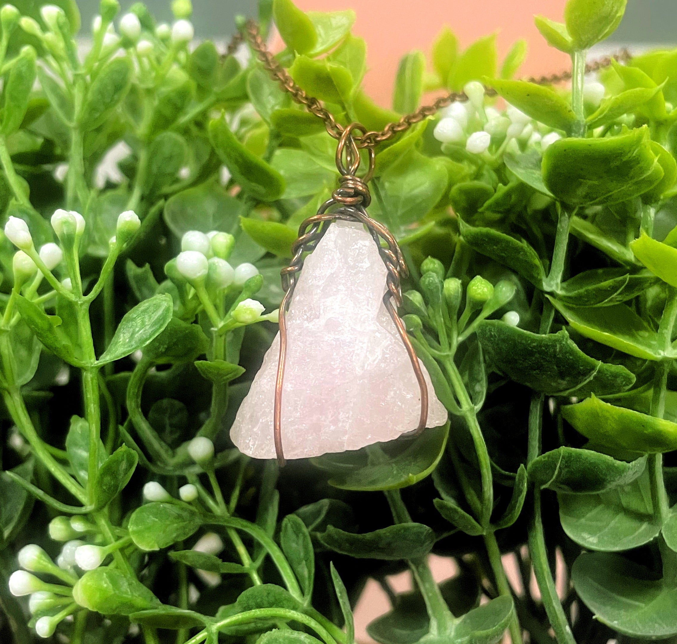 Wire Wrapped Rough Rose Quartz Gemstone Pendant on a 21-inch cord, showcasing its oxidized copper wire wrapping and natural beauty.
