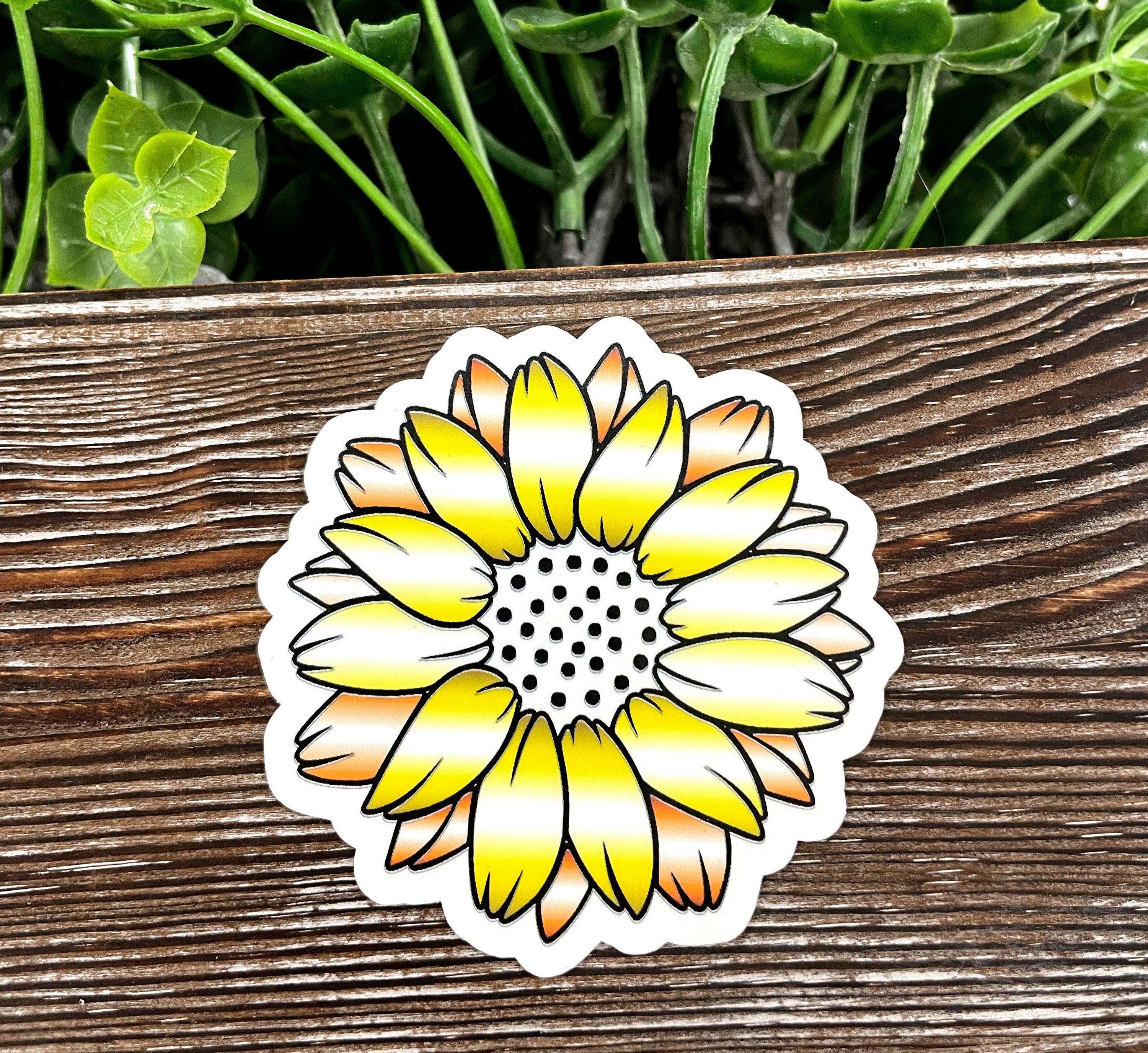 A vibrant yellow flower die cut sticker on a smooth surface, showcasing its intricate design and water-resistant laminate finish.