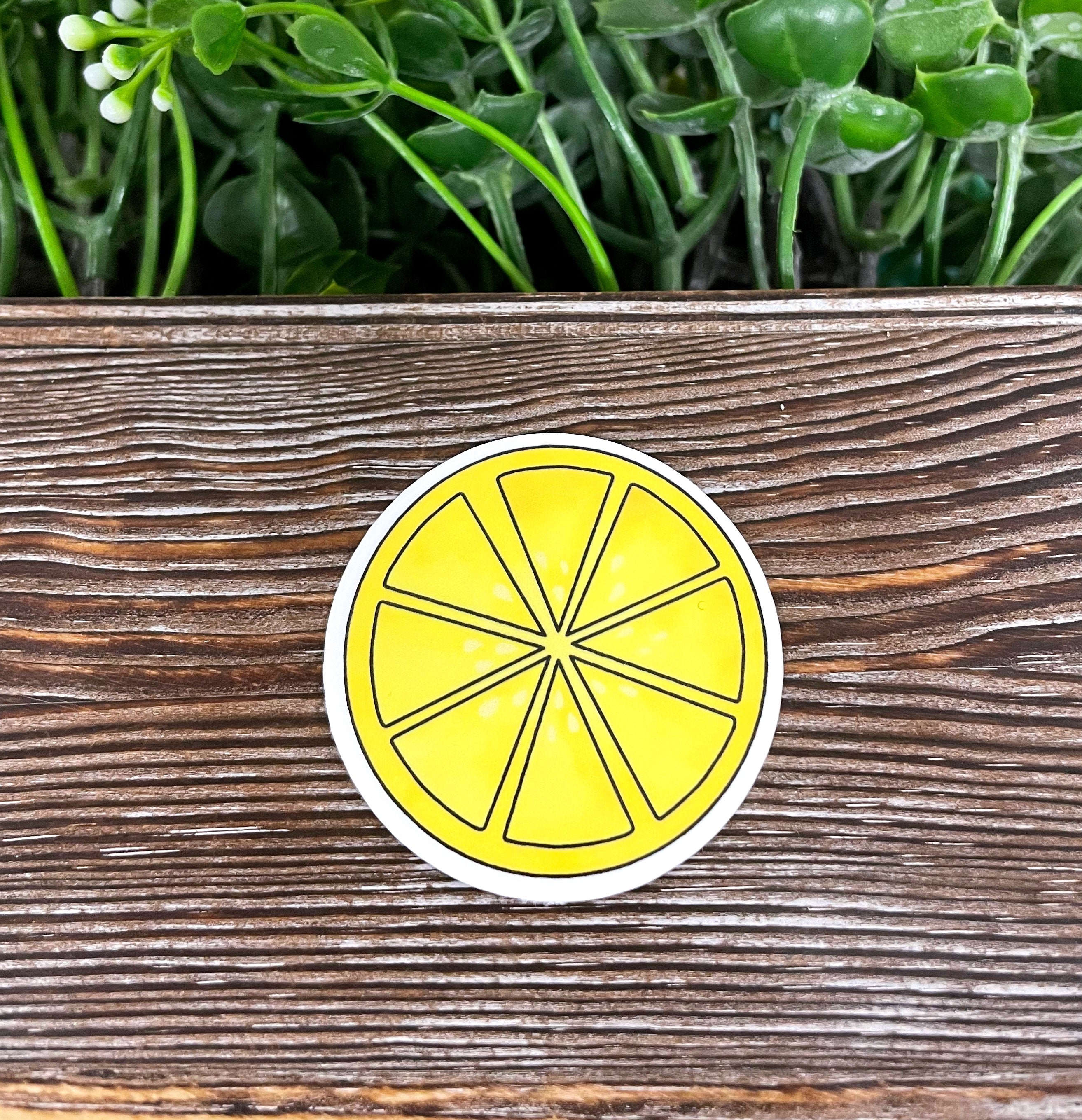 A vibrant yellow lemon slice die cut sticker on a smooth surface, showcasing its bright colors and graphic art design.