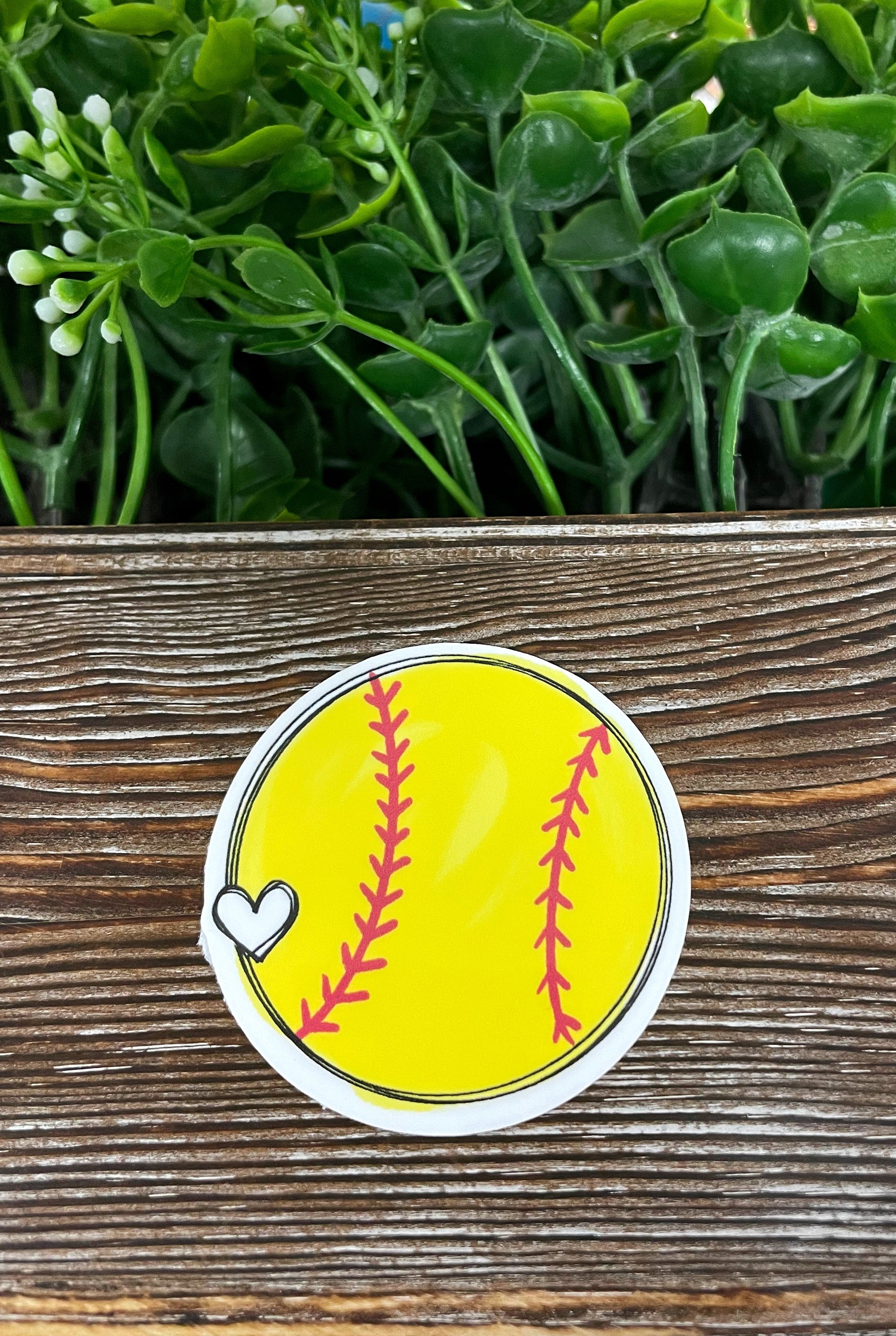Yellow die cut sticker featuring a softball with a heart design, perfect for personalizing smooth surfaces.