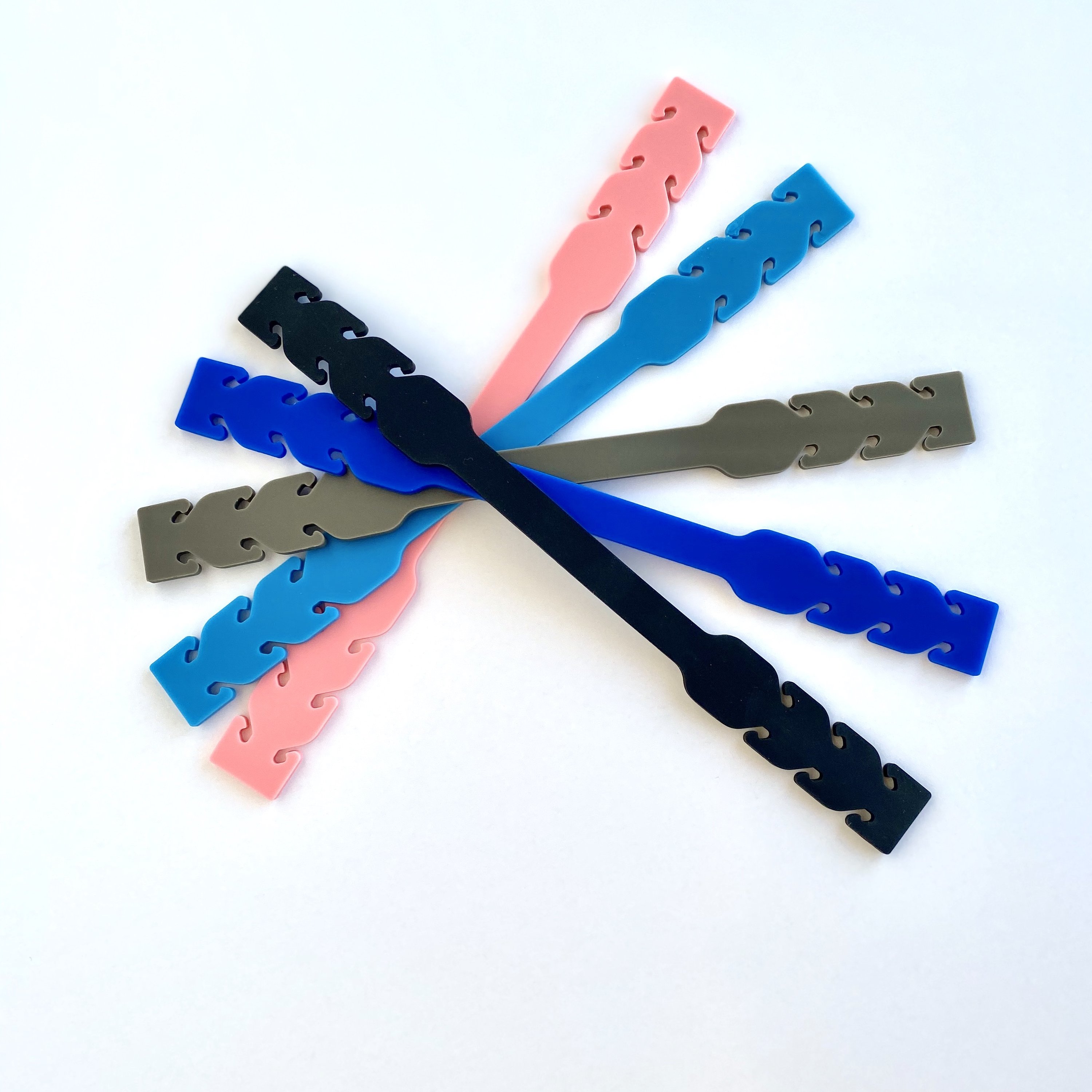 A colorful assortment of 5 silicone mask extenders in black, light blue, royal blue, gray, and pink, designed for comfort and ear relief.