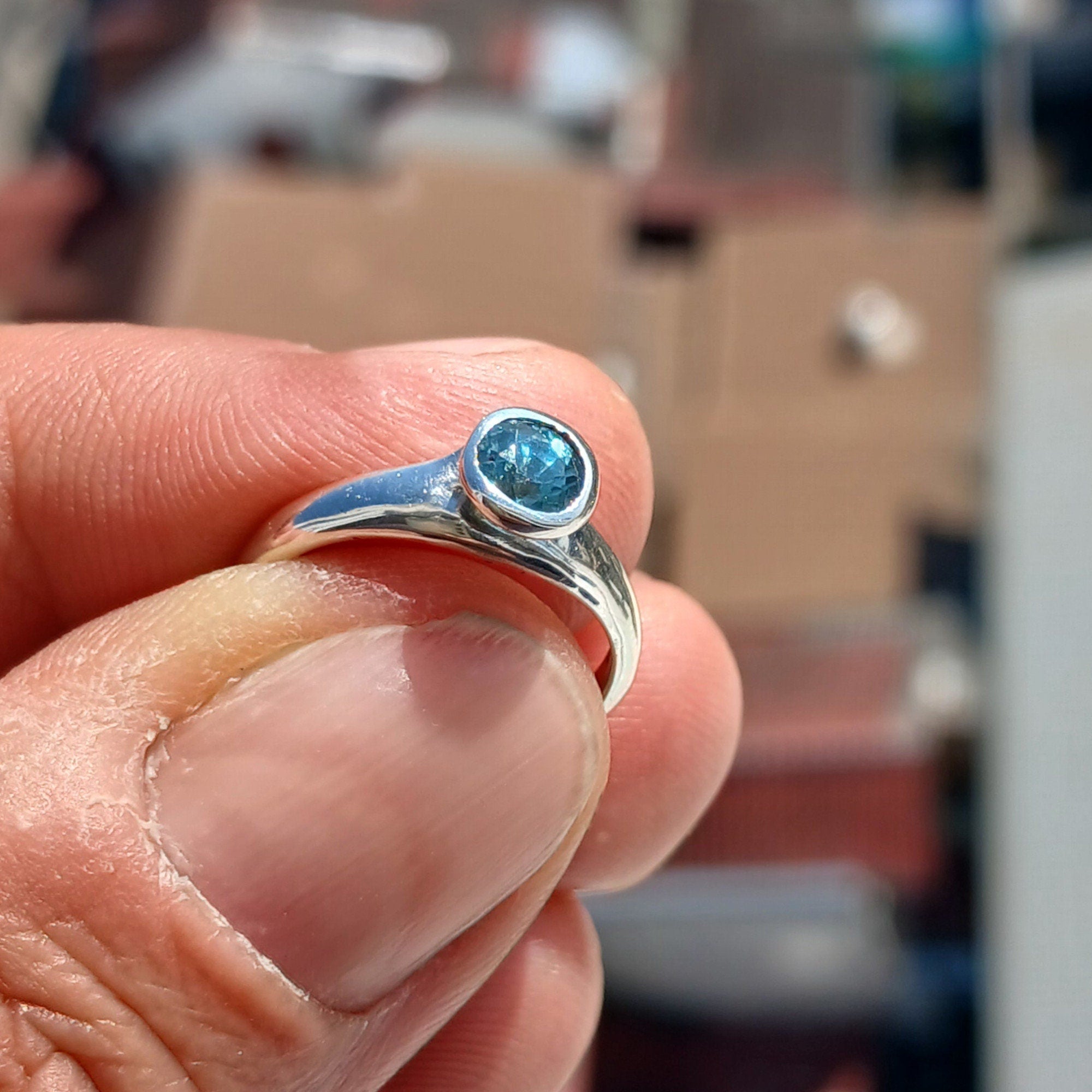 A beautiful Blue Zircon Ring set in polished sterling silver, showcasing a minimalist design with a sparkling blue gemstone.
