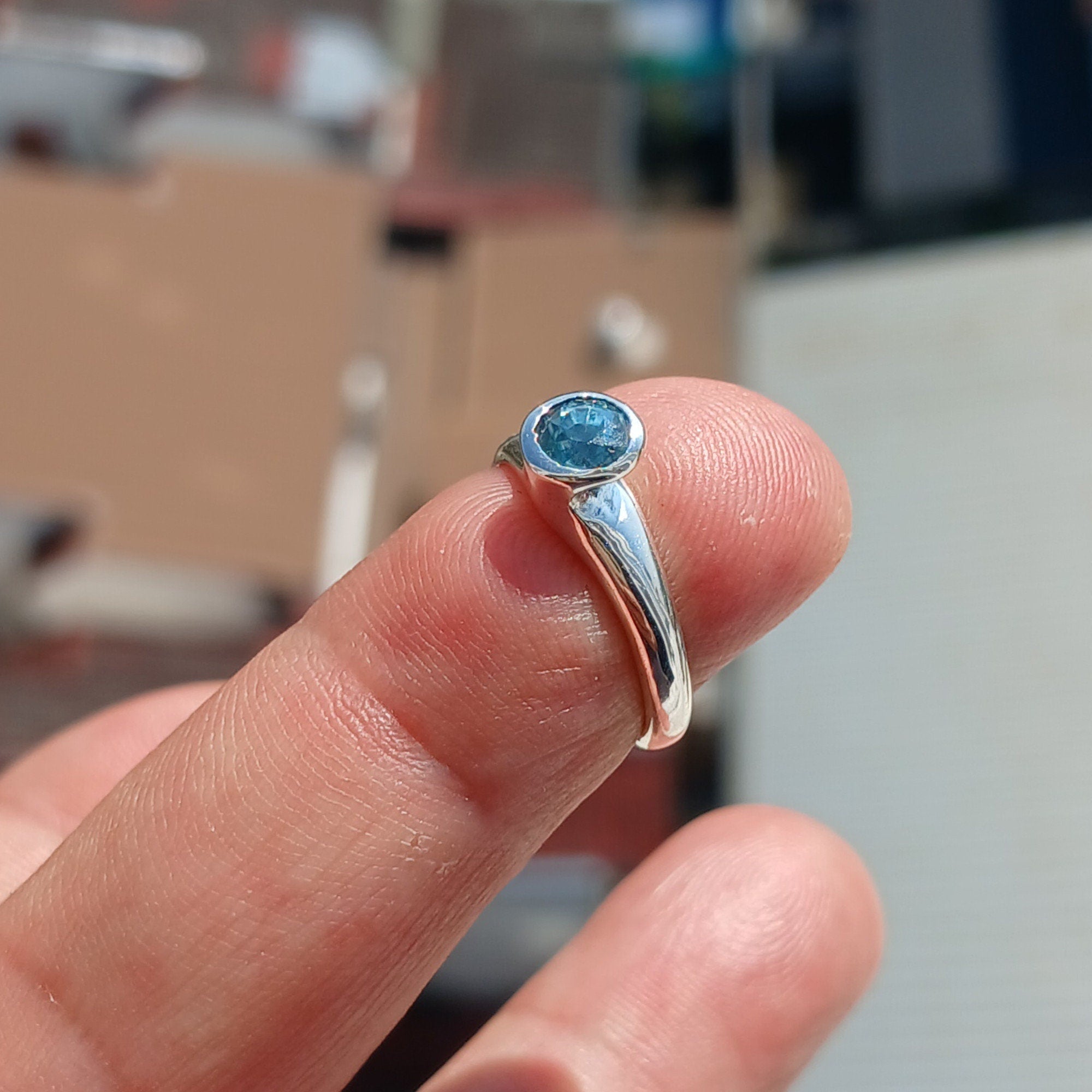 A beautiful Blue Zircon Ring set in polished sterling silver, showcasing a minimalist design with a sparkling blue gemstone.