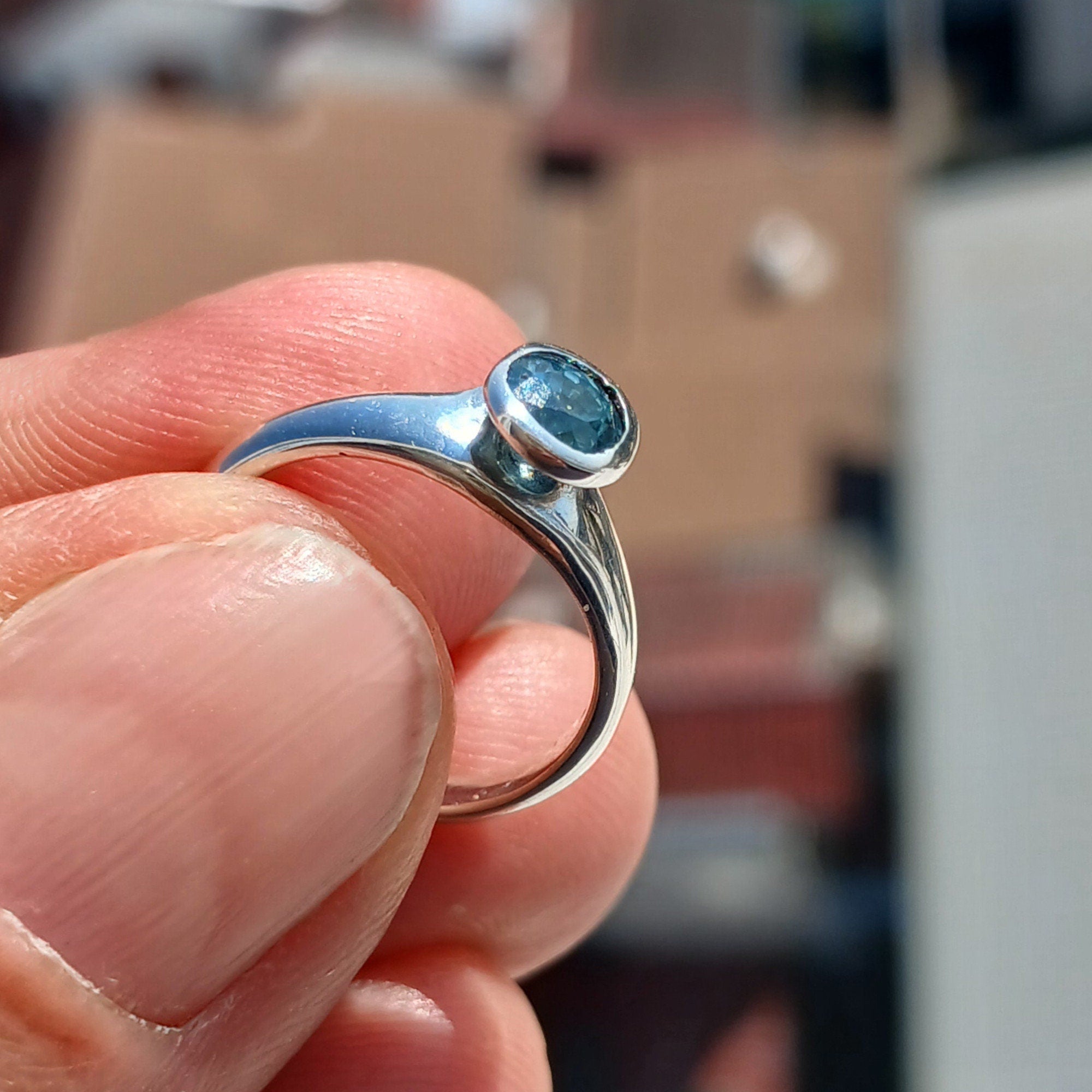 A beautiful Blue Zircon Ring set in polished sterling silver, showcasing a minimalist design with a sparkling blue gemstone.