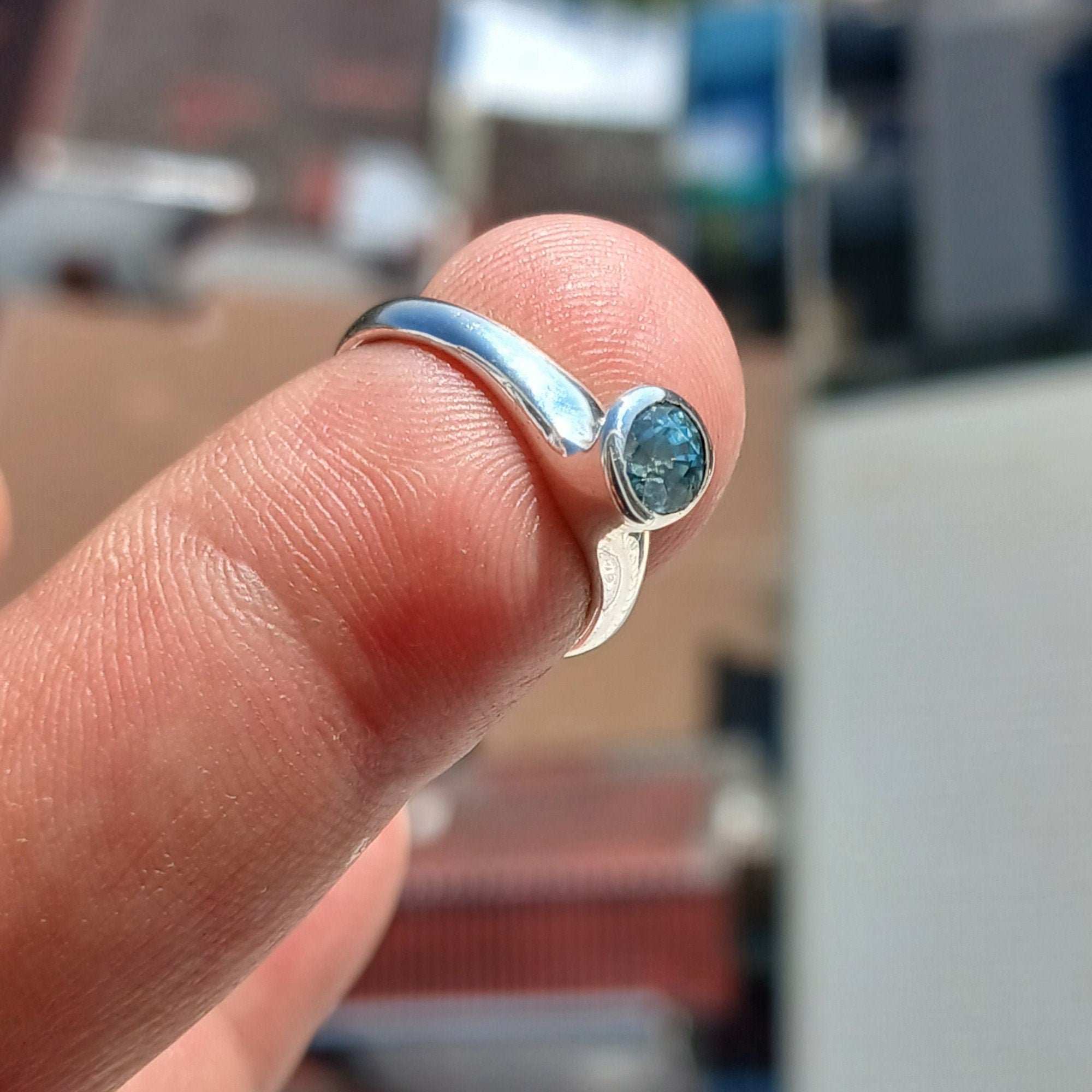 A beautiful Blue Zircon Ring set in polished sterling silver, showcasing a minimalist design with a sparkling blue gemstone.