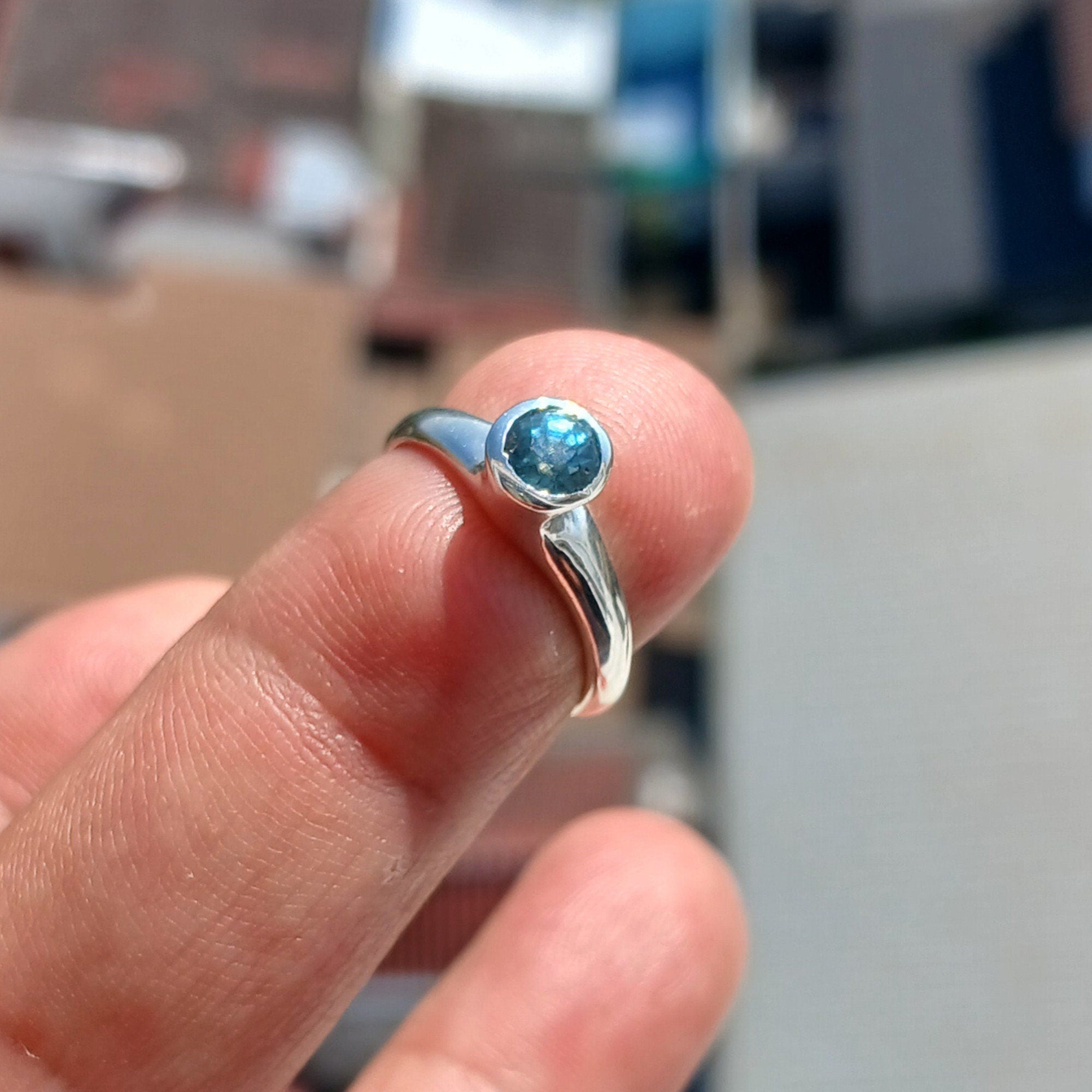 A beautiful Blue Zircon Ring set in polished sterling silver, showcasing a minimalist design with a sparkling blue gemstone.
