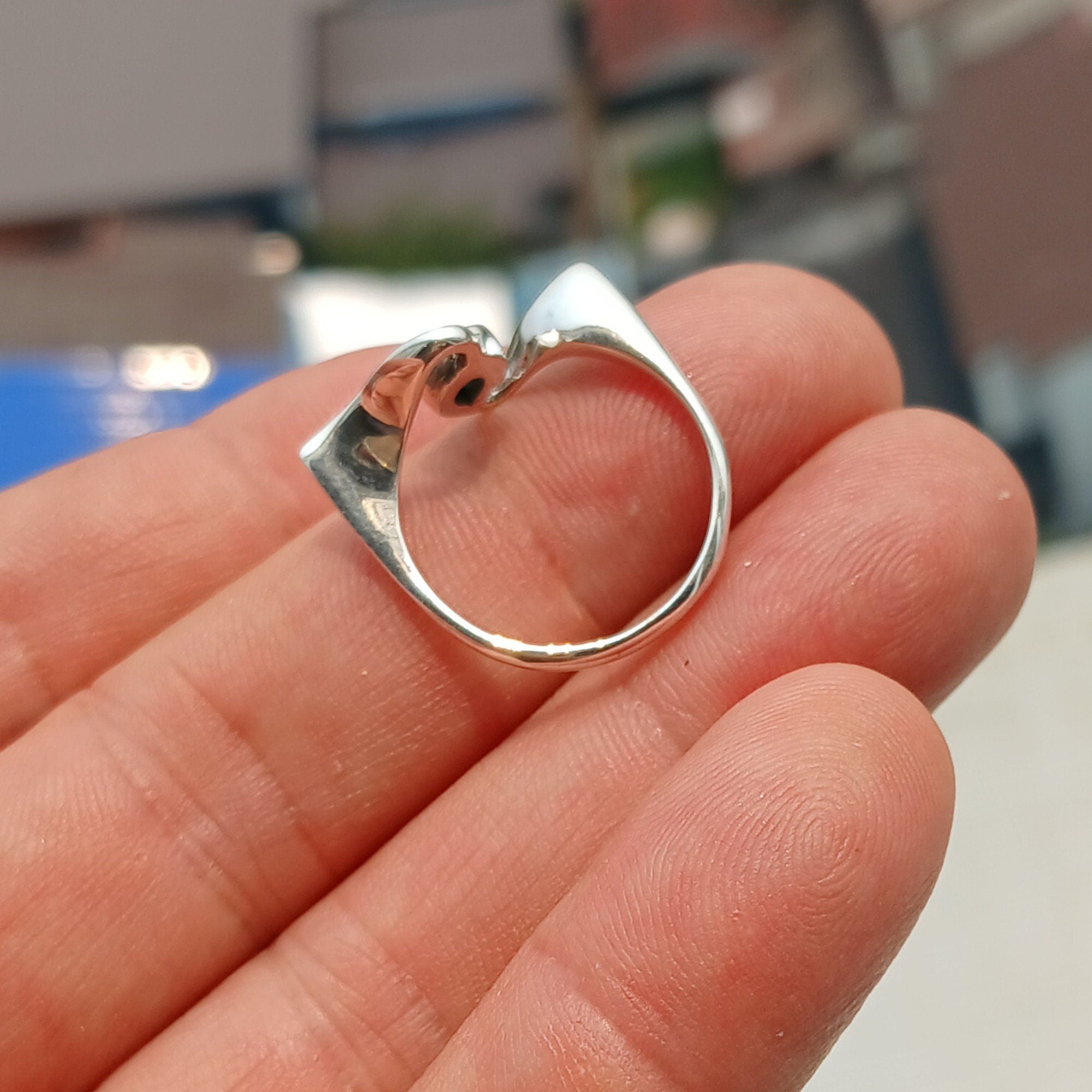 A polished sterling silver ring featuring a pear-shaped natural green emerald, showcasing its vibrant color and elegant design.