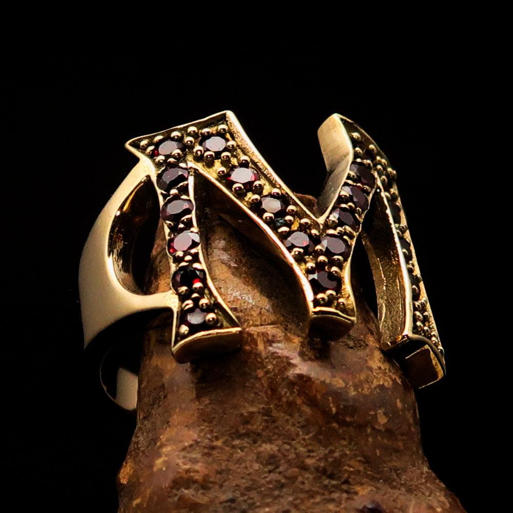 A beautifully crafted Initial Ring featuring a bold Letter M, embellished with 21 red Cubic Zirconias, made from solid Brass with a mirror polished finish.