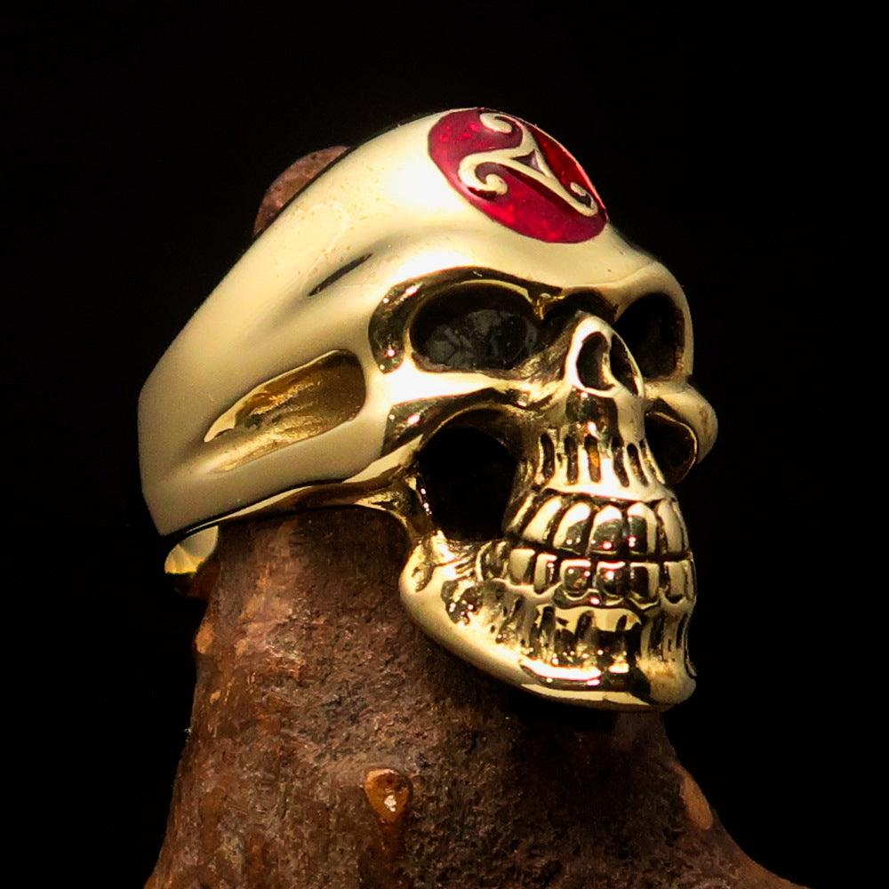Men's Celtic Triskelia Triad Skull Ring in solid brass with red enamel accents, showcasing intricate design and high-polished finish.