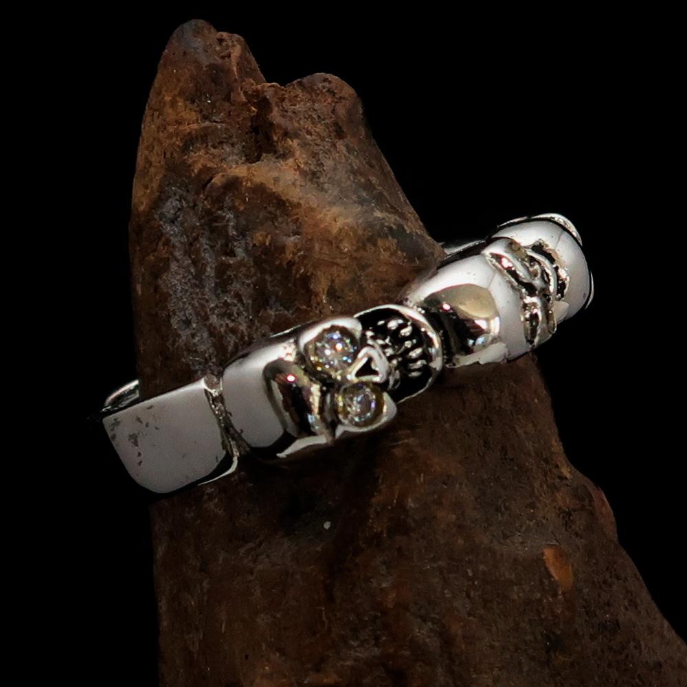 Men's sterling silver band ring featuring 6 small skulls with white cubic zirconia eyes, showcasing a polished and antiqued finish.