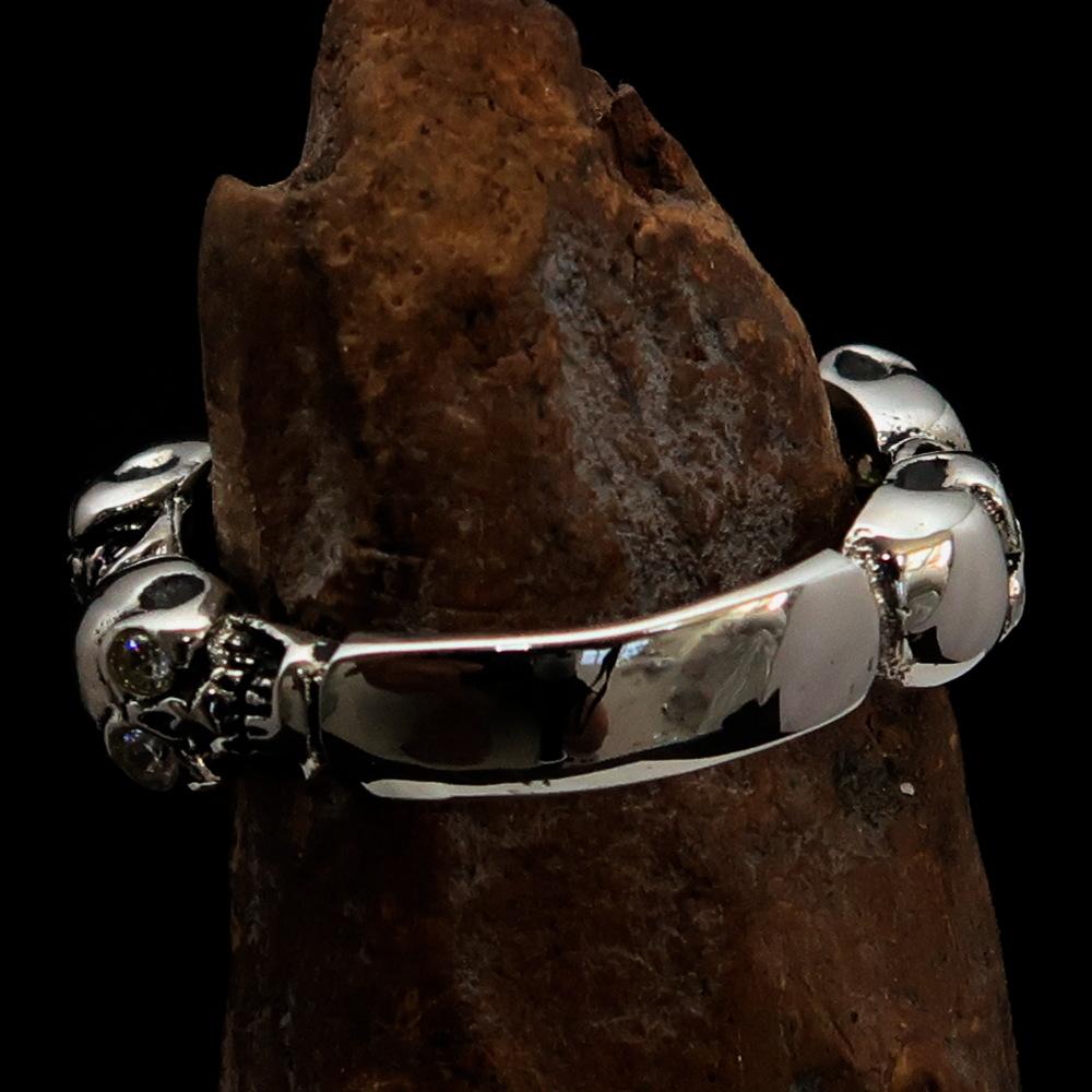 Men's sterling silver band ring featuring 6 small skulls with white cubic zirconia eyes, showcasing a polished and antiqued finish.
