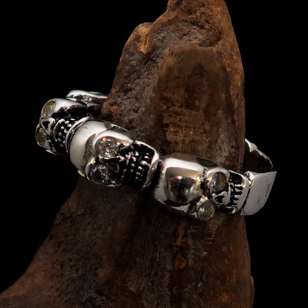 Men's sterling silver band ring featuring 6 small skulls with white cubic zirconia eyes, showcasing a polished and antiqued finish.